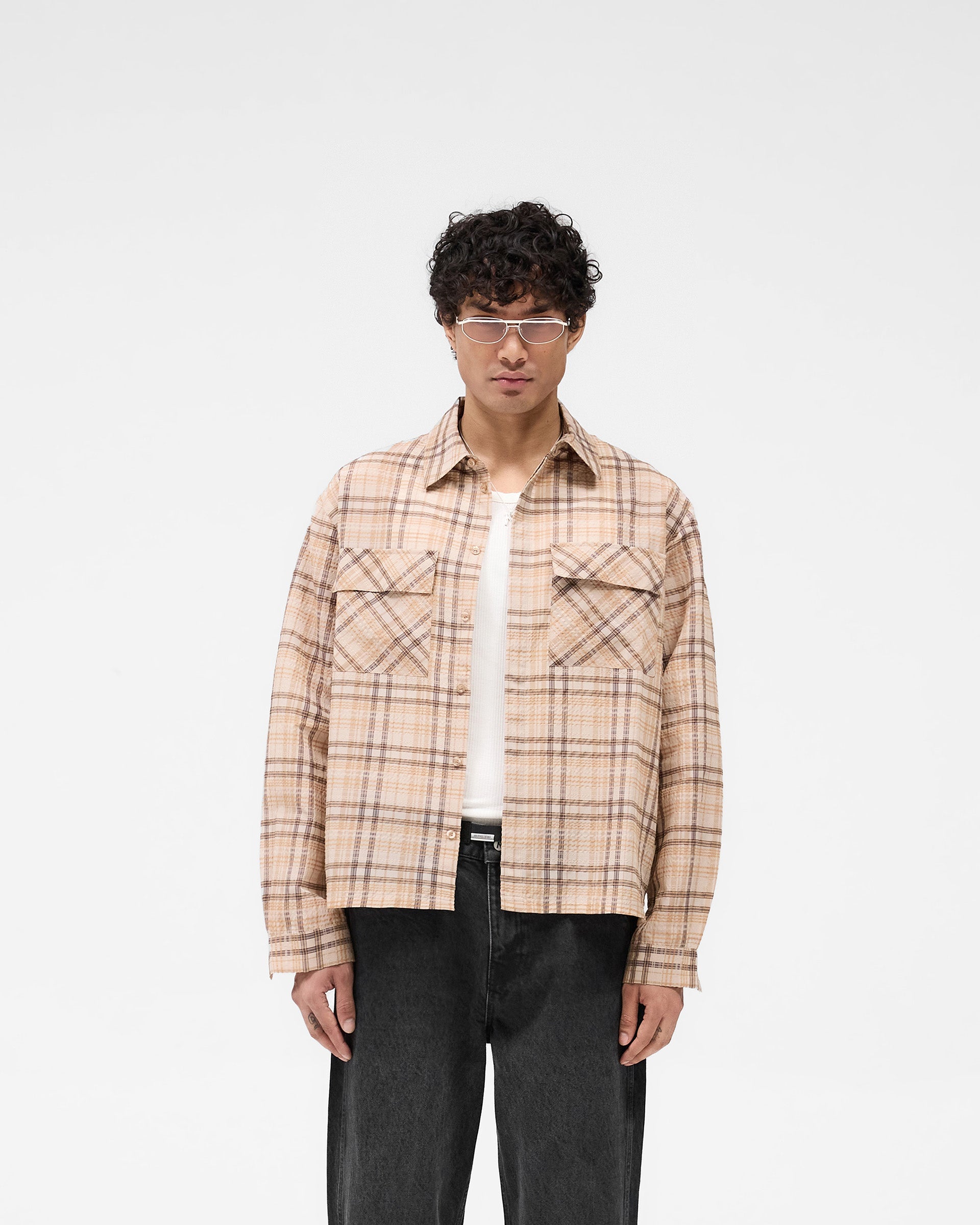 Man wearing a brown check flannel shirt on a plain white background | Sheer Flannel Shirt in Brown Check | Lightweight breathable shirt with dual chest pockets | SS25 Shirts | Represent Clo