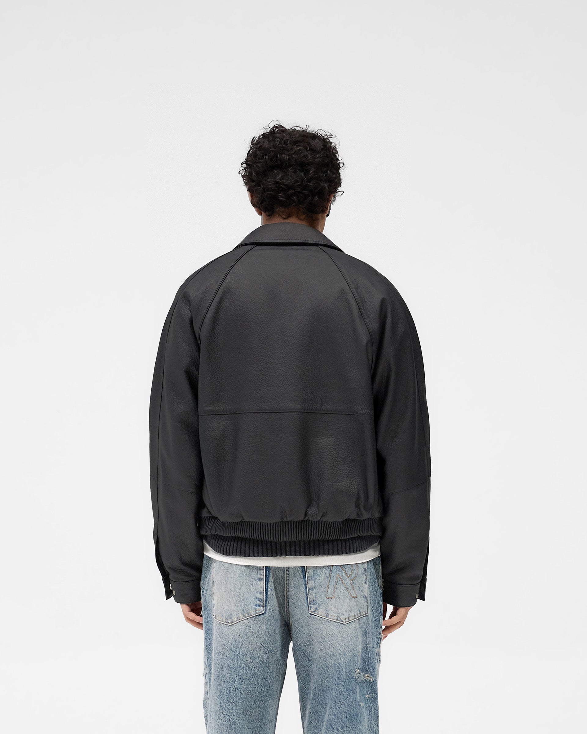 Man wearing a black leather jacket on a plain white background | Overdrive Leather Jacket in Black | Leather jacket with oversized fit and logo zip | SS25 Outerwear | Represent Clo
