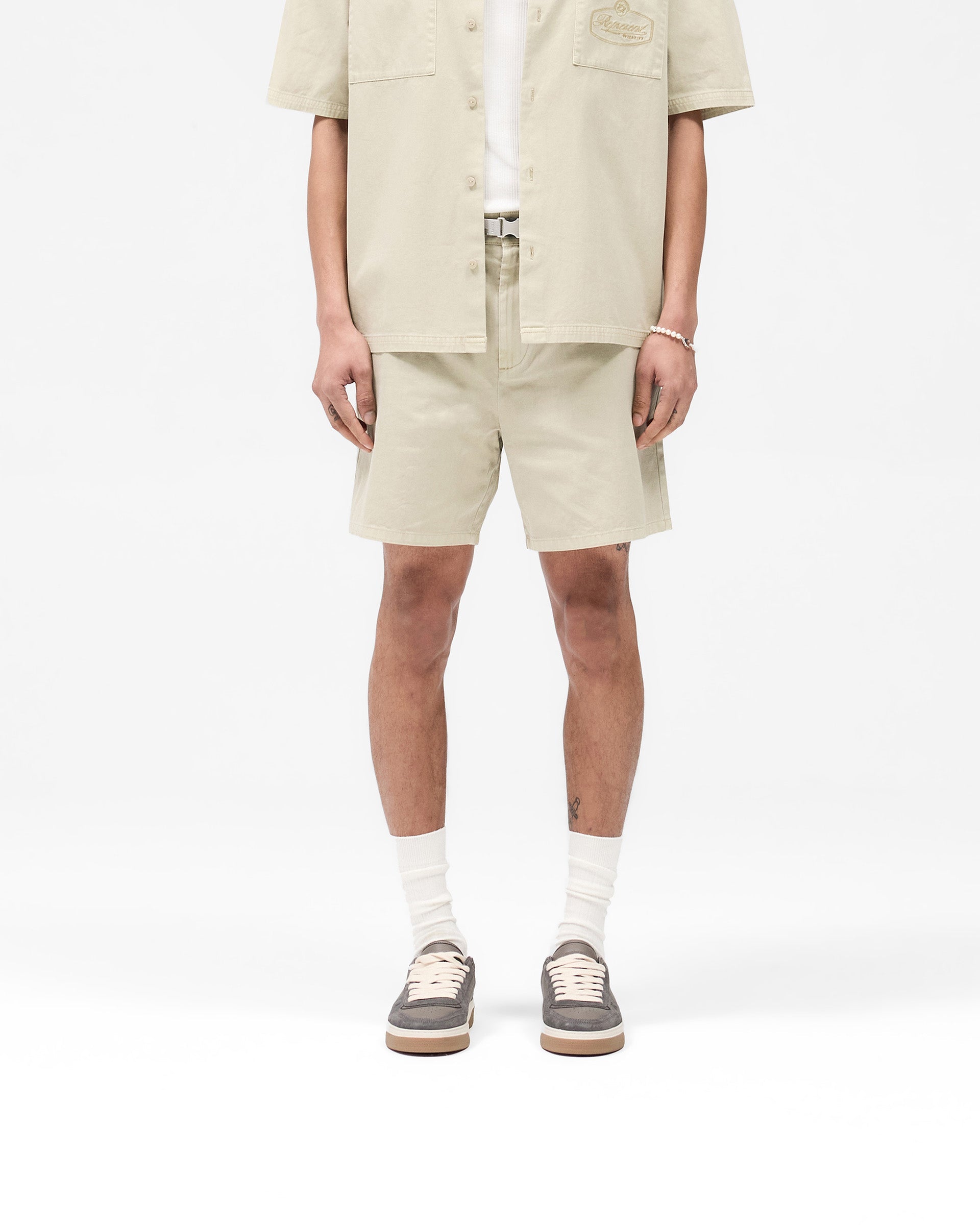 Man wearing beige shorts on a plain white background | Cotton Tailored Short in Beige | Tailored shorts with structured silhouette | SS25 Shorts | Represent Clo
