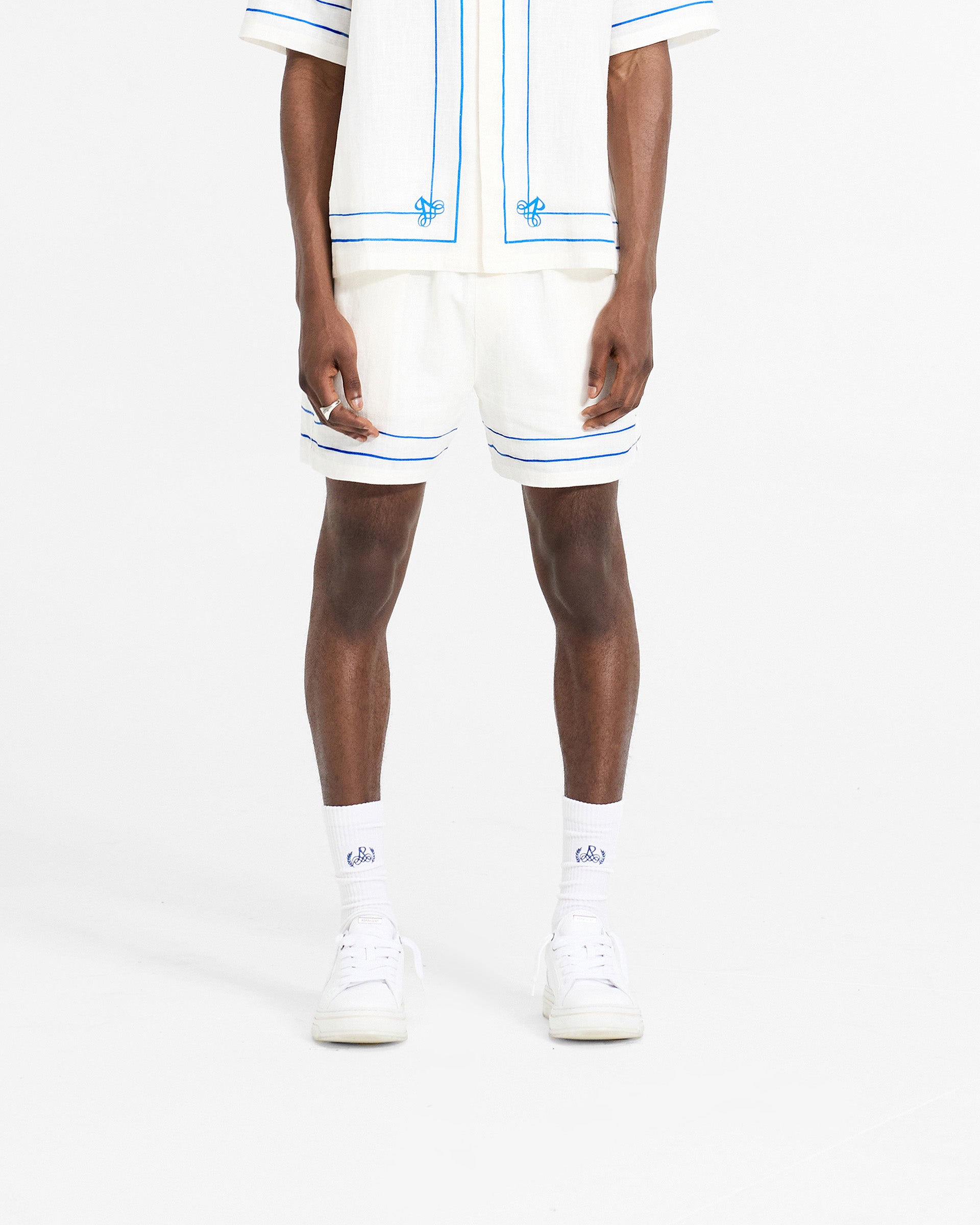 Man wearing white shorts on a plain white background | Permanent Vacation Short in Flat White | Lightweight shorts with elasticated waistband and drawcord | SC24 Shorts | Represent Clo