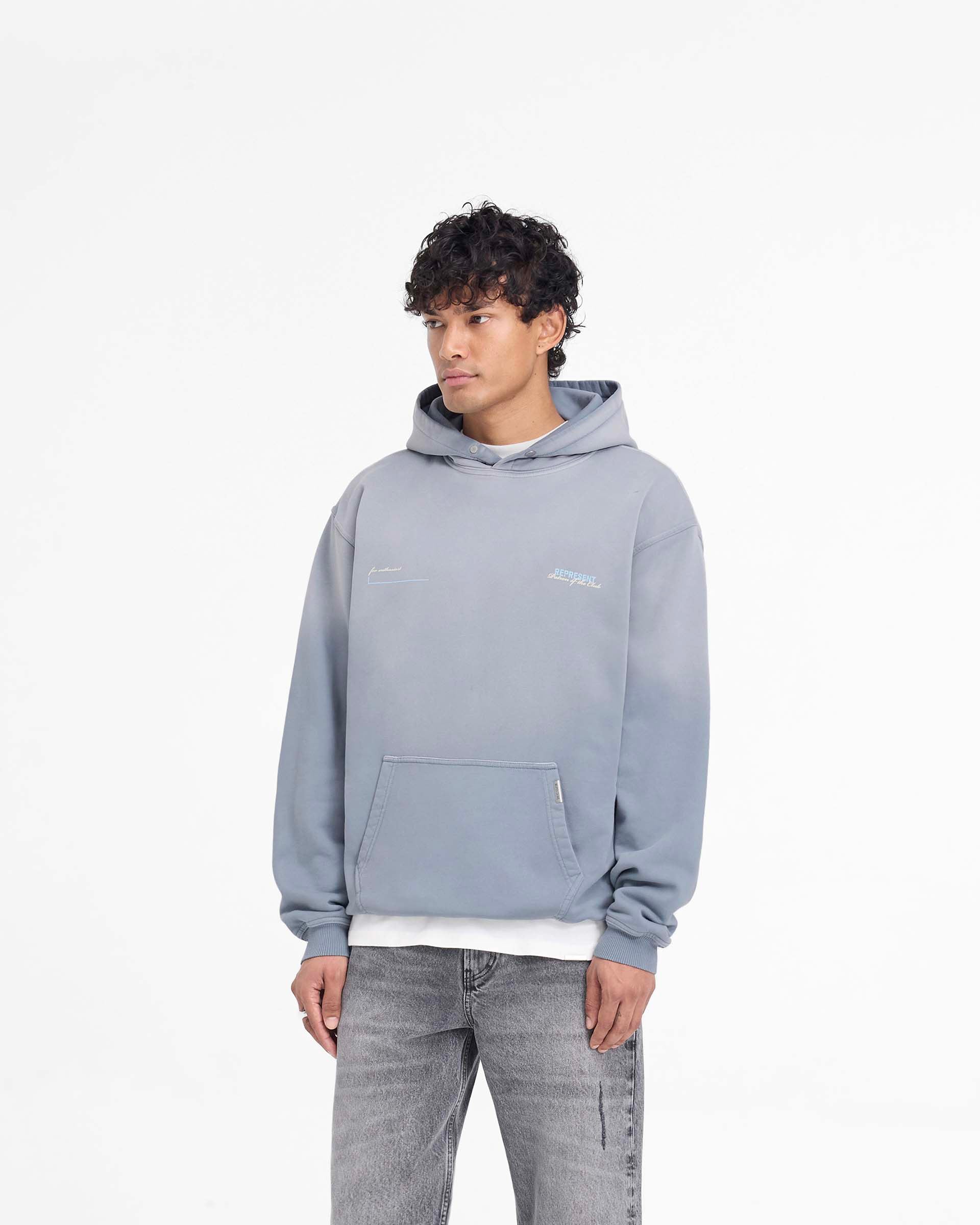 Man wearing an oversized grey hoodie on a plain white background | Patron Of The Club Hoodie in Washed Grey | Oversized hoodie with unique wash and Patron of the Club print | Patrons Hoodies | Represent Clo