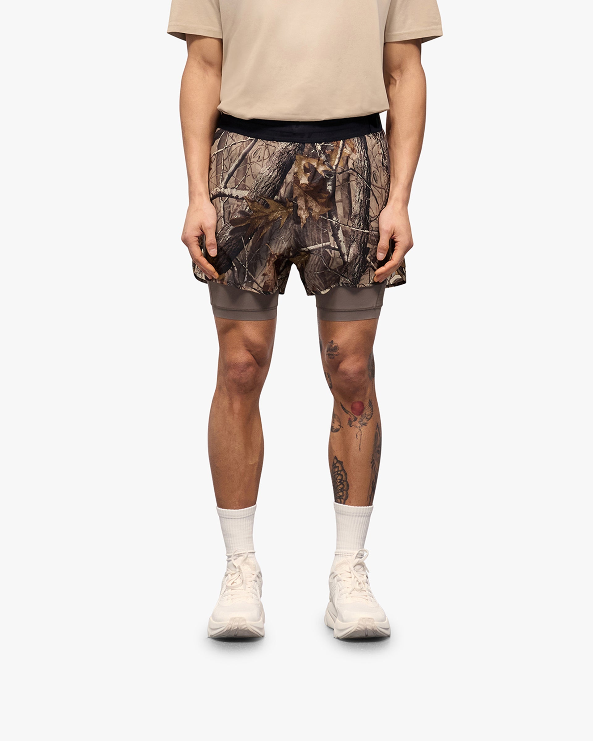 Man wearing printed shorts on a plain white background | 247 Contour 2-In-1 Run Shorts in Realtree | Shorts with inner legging and pockets | 247 Shorts | Represent Clo