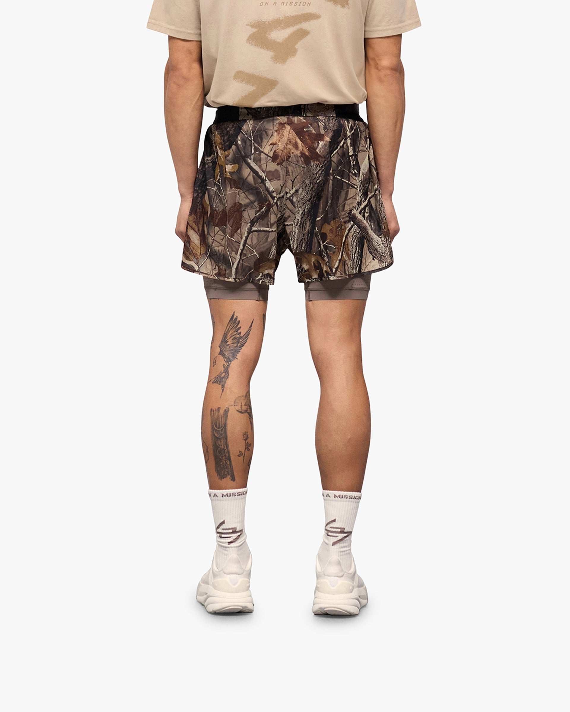 Man wearing a brown shorts on a plain white background | 247 Contour 2-In-1 Run Shorts in Realtree | Shorts with inner legging for support and mobility | 247 Shorts | Represent Clo