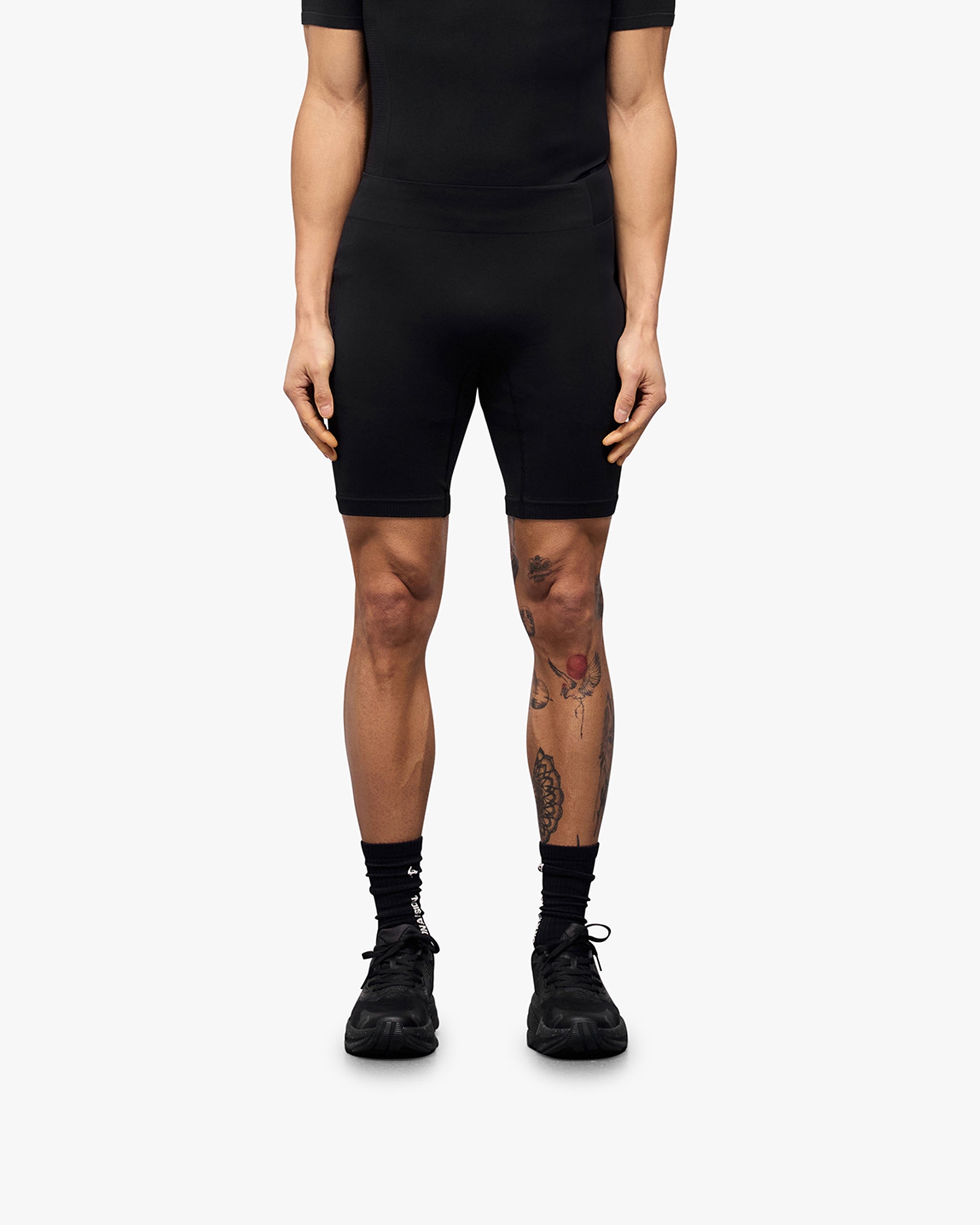 Man wearing black seamless shorts on a plain white background | 247 DNA Seamless Shorts in Black | Seamless half tights with compression support | 247 Shorts | Represent Clo