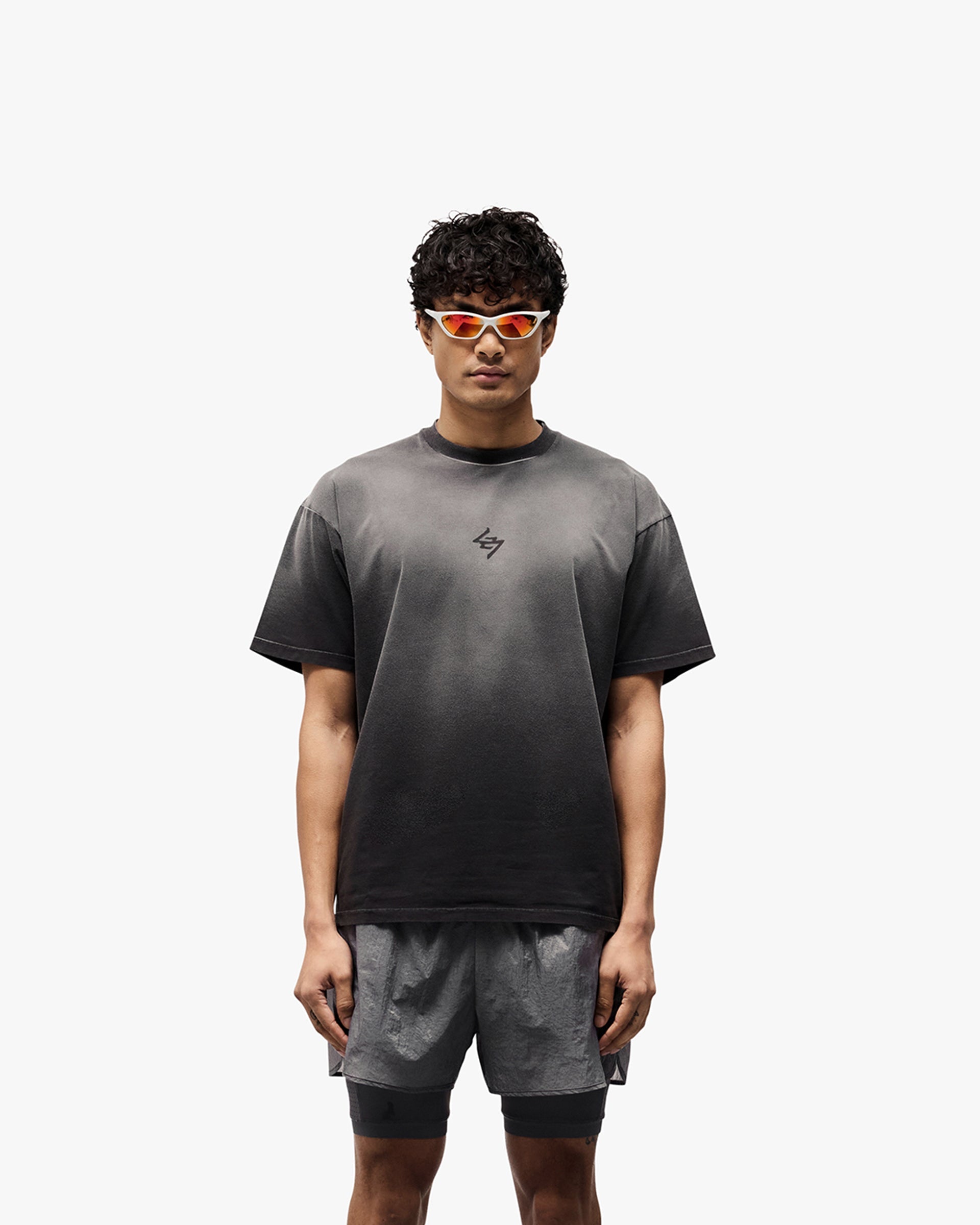 Man wearing an oversized black t-shirt with graphic print on a plain white background | 247 Motion Oversized T-Shirt in Aged Black | Oversized t-shirt with sweat wicking and antibacterial properties | 247 T-Shirts | Represent Clo