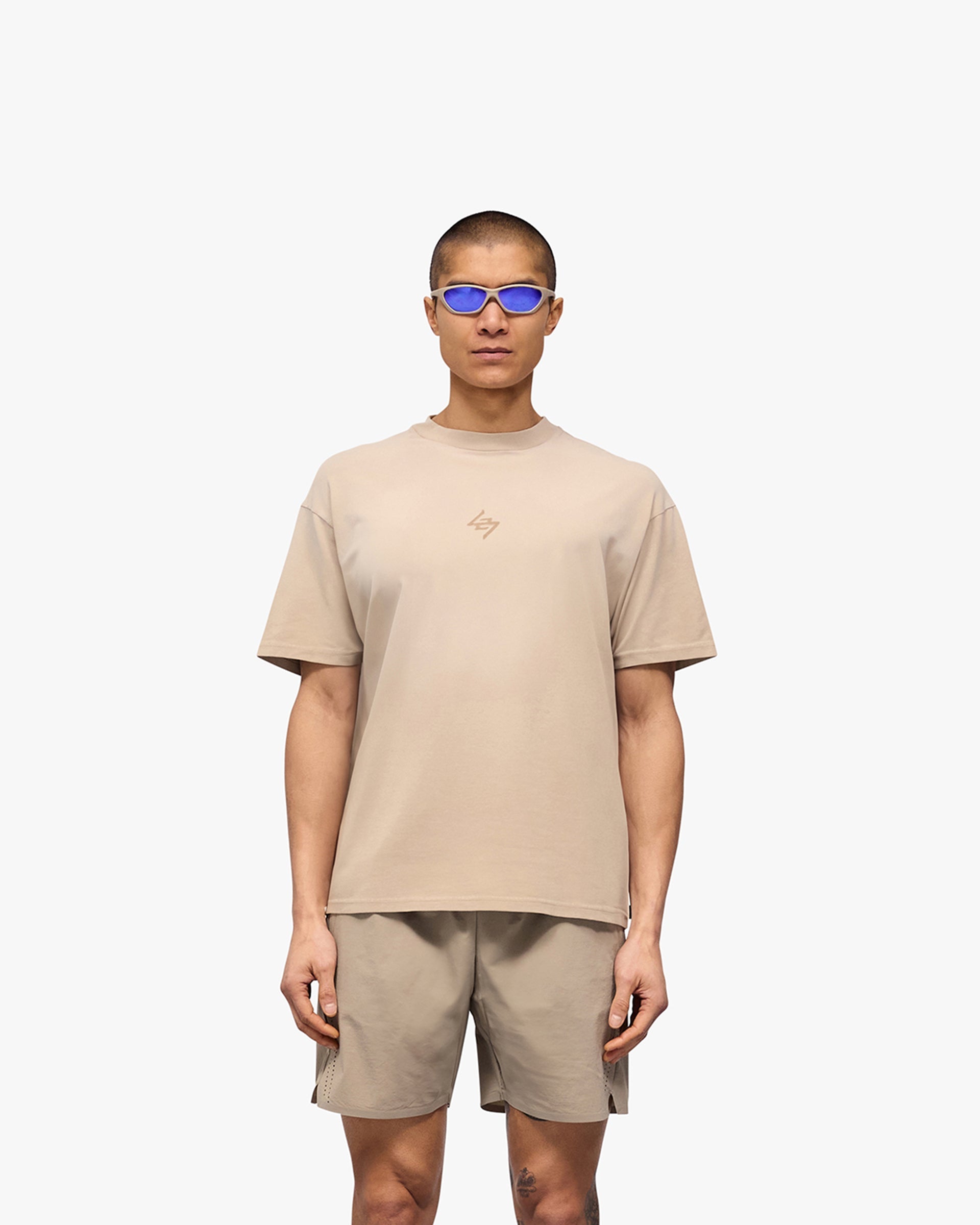 Man wearing a grey t-shirt on a plain white background | 247 Motion Oversized T-Shirt in Pebble | Oversized t-shirt with sweat wicking fabric | 247 T-Shirts | Represent Clo