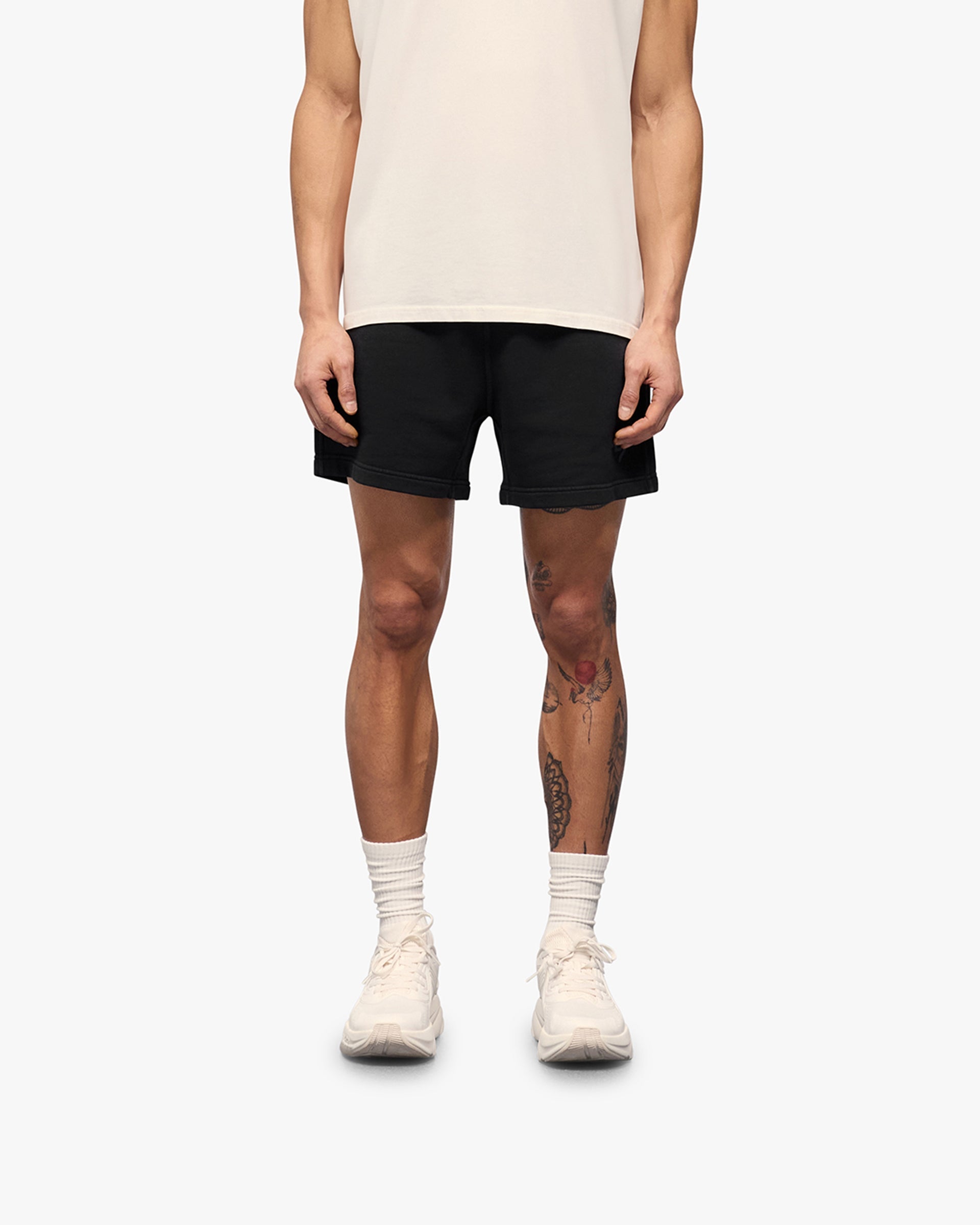 Man wearing aged black shorts on a plain white background | 247 Motion Shorts in Aged Black | Jersey shorts with elasticated waistband | 247 Shorts | Represent Clo