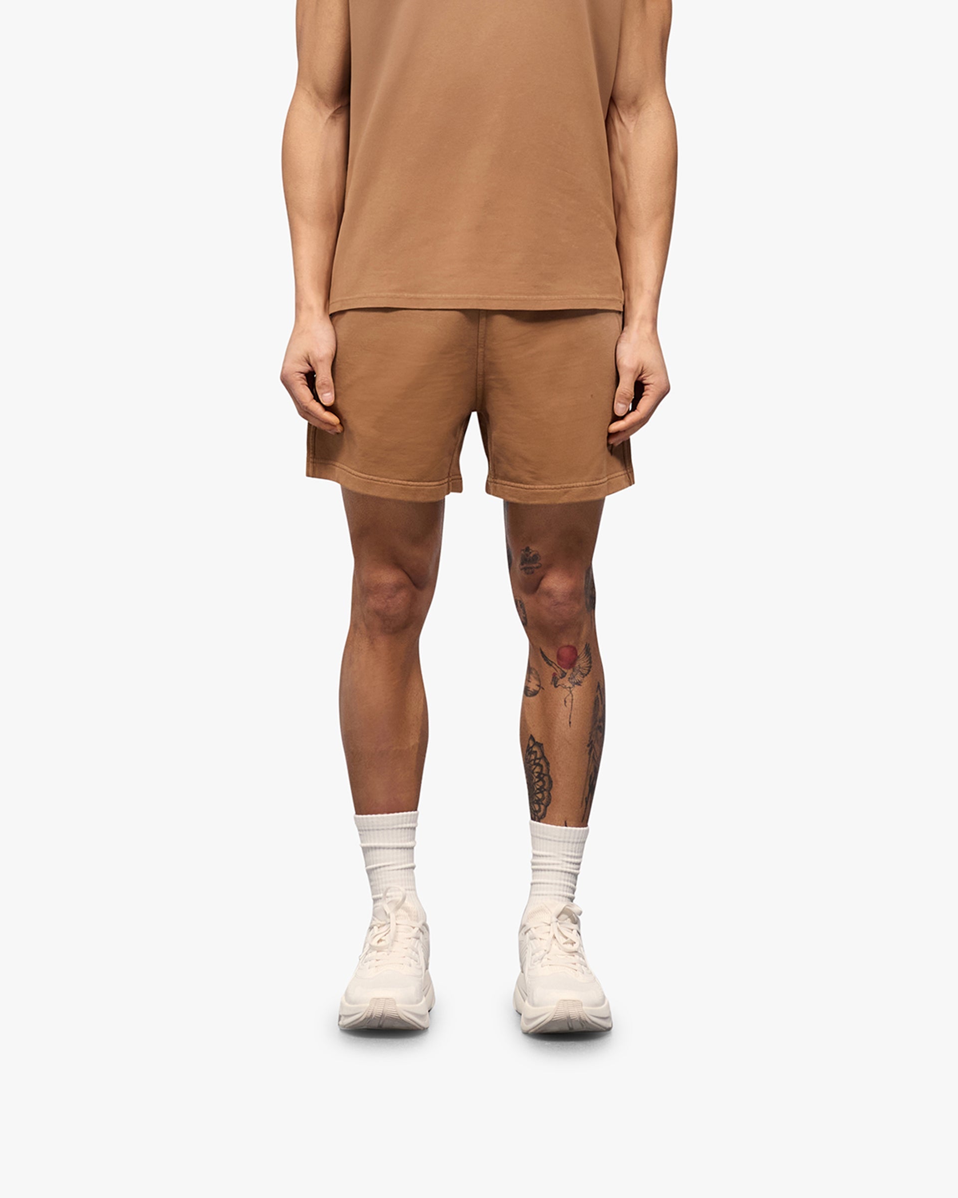 Man wearing rust shorts on a plain white background | 247 Motion Shorts in Rust | Jersey shorts with elasticated waistband and water based graphic print | 247 Shorts | Represent Clo