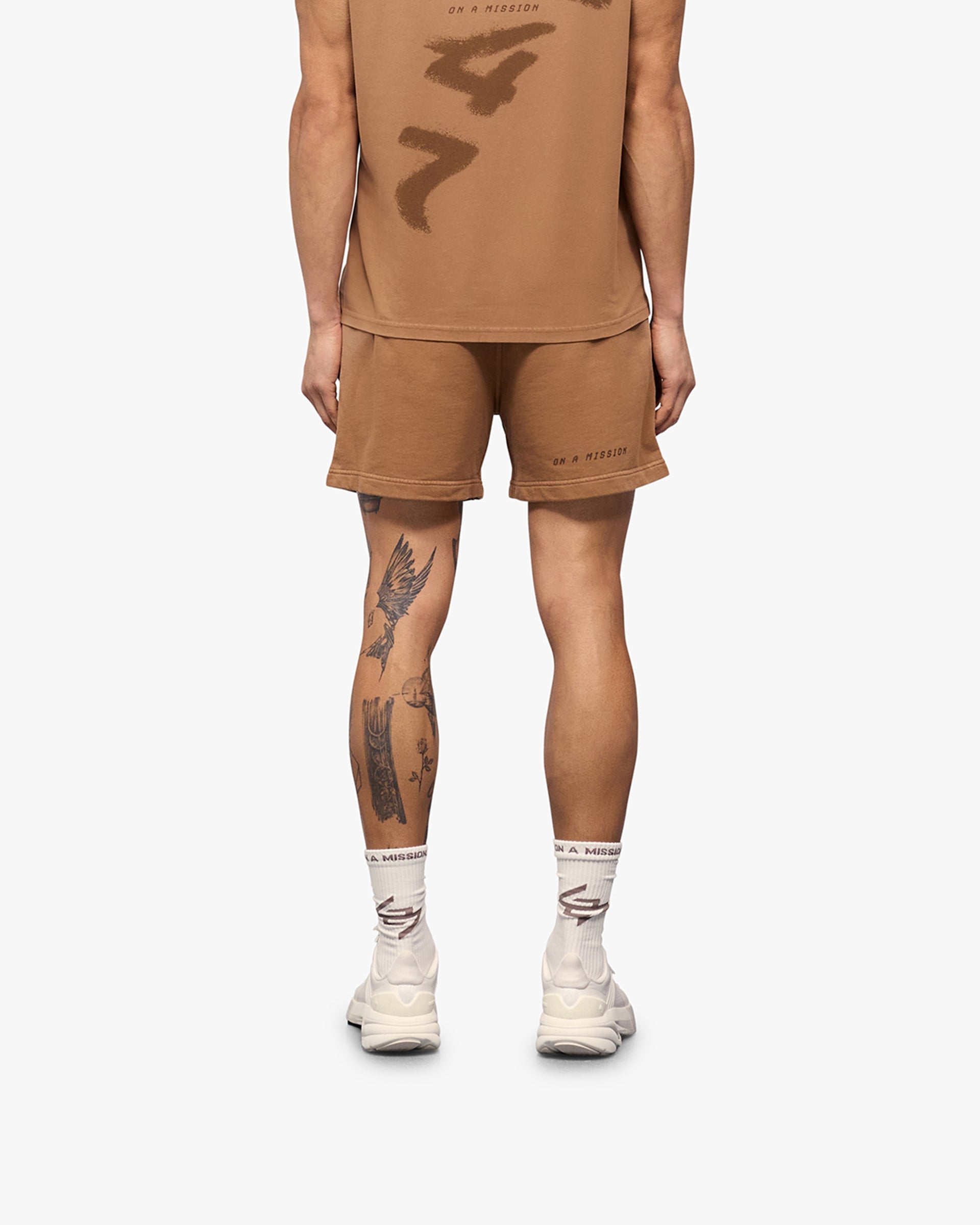 Man wearing russet shorts on a plain white background | 247 Motion Shorts in Rust | Jersey shorts with elasticated waistband and vintage wash | 247 Shorts | Represent Clo