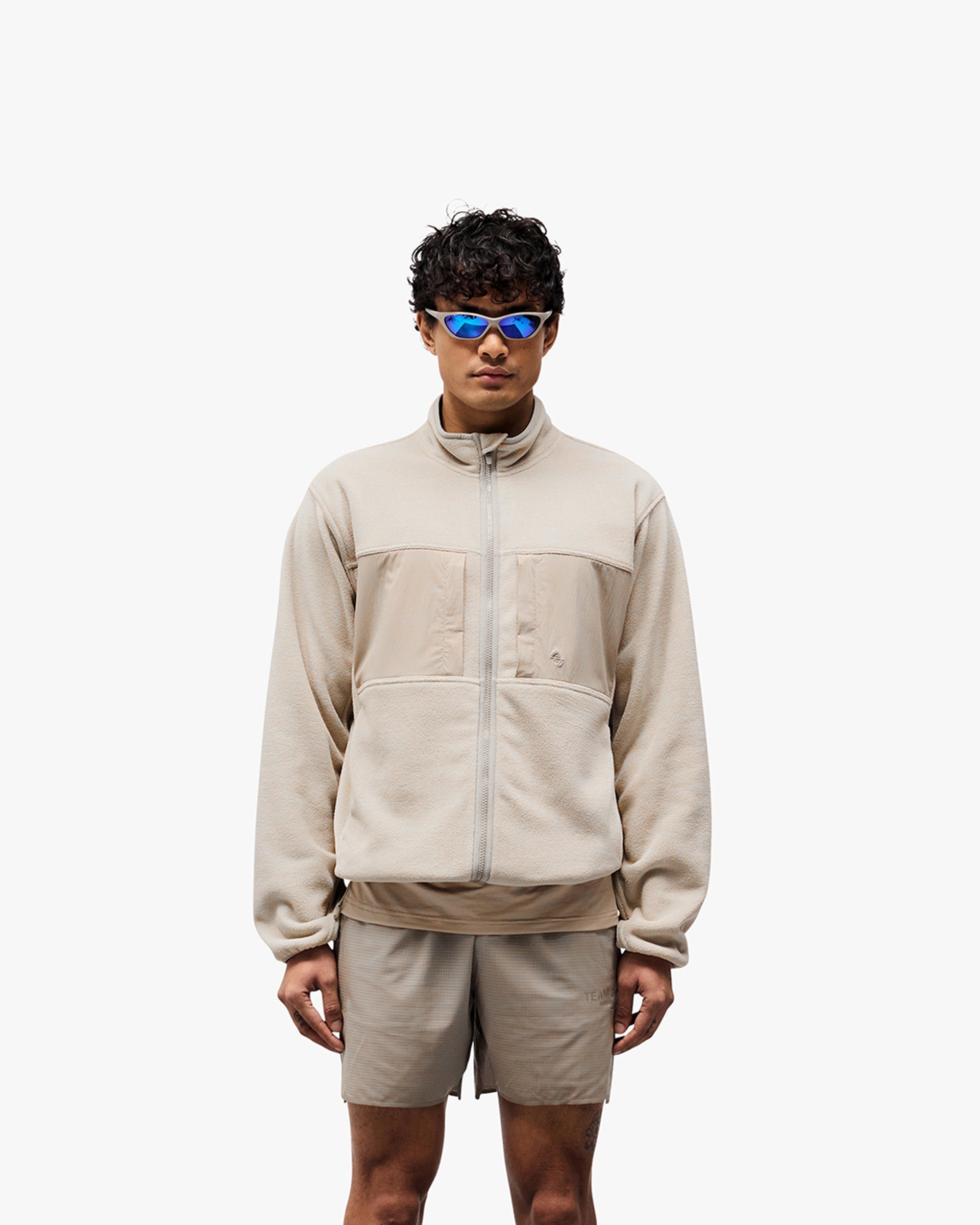 Man wearing a grey fleece on a plain white background | 247 Polar Panelled Fleece in Pebble | Fleece with toggle hem and zip pockets | 247 Outerwear | Represent Clo