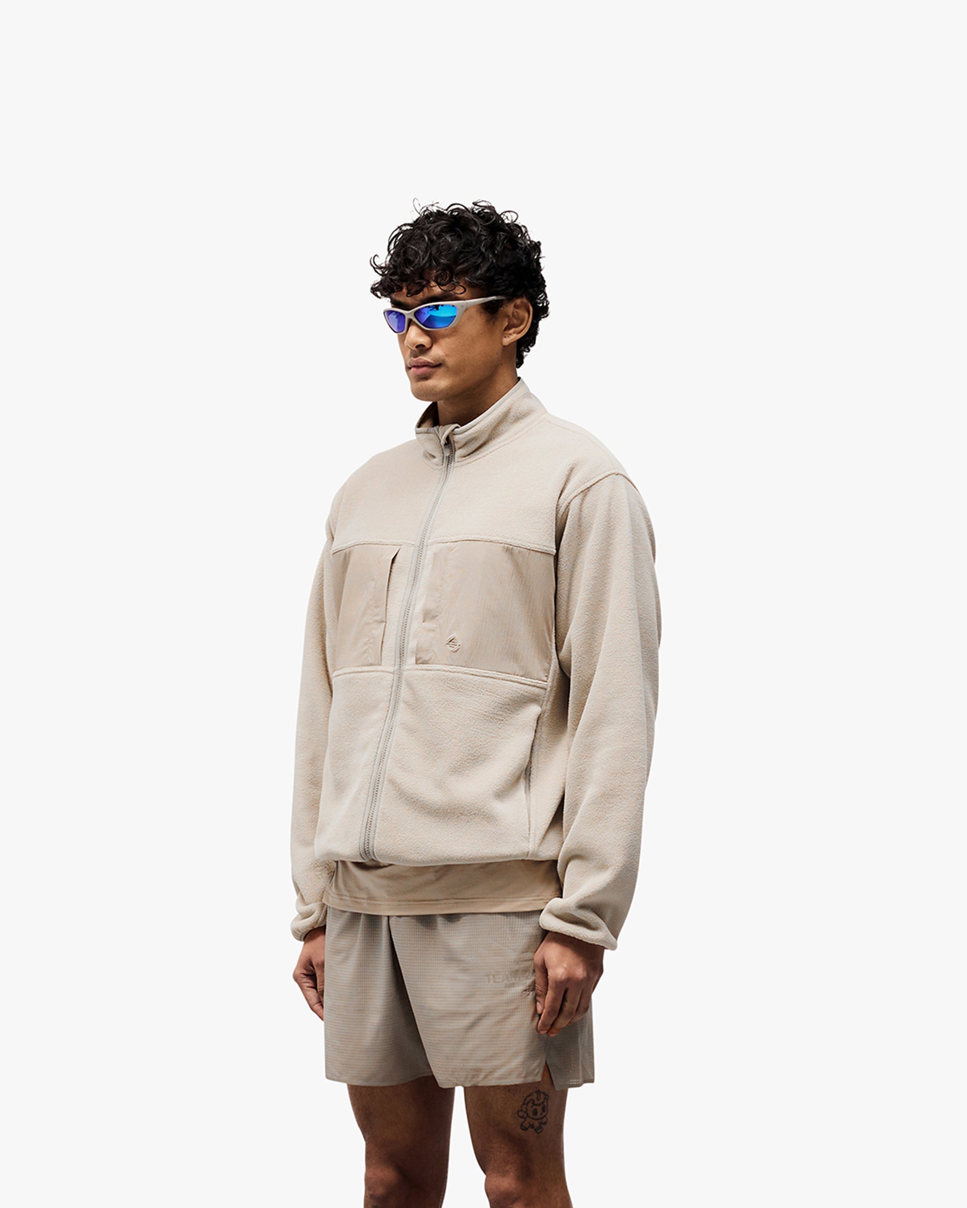 Man wearing a grey fleece on a plain white background | 247 Polar Panelled Fleece in Pebble | Fleece with double-ended zip and toggle hem | 247 Outerwear | Represent Clo