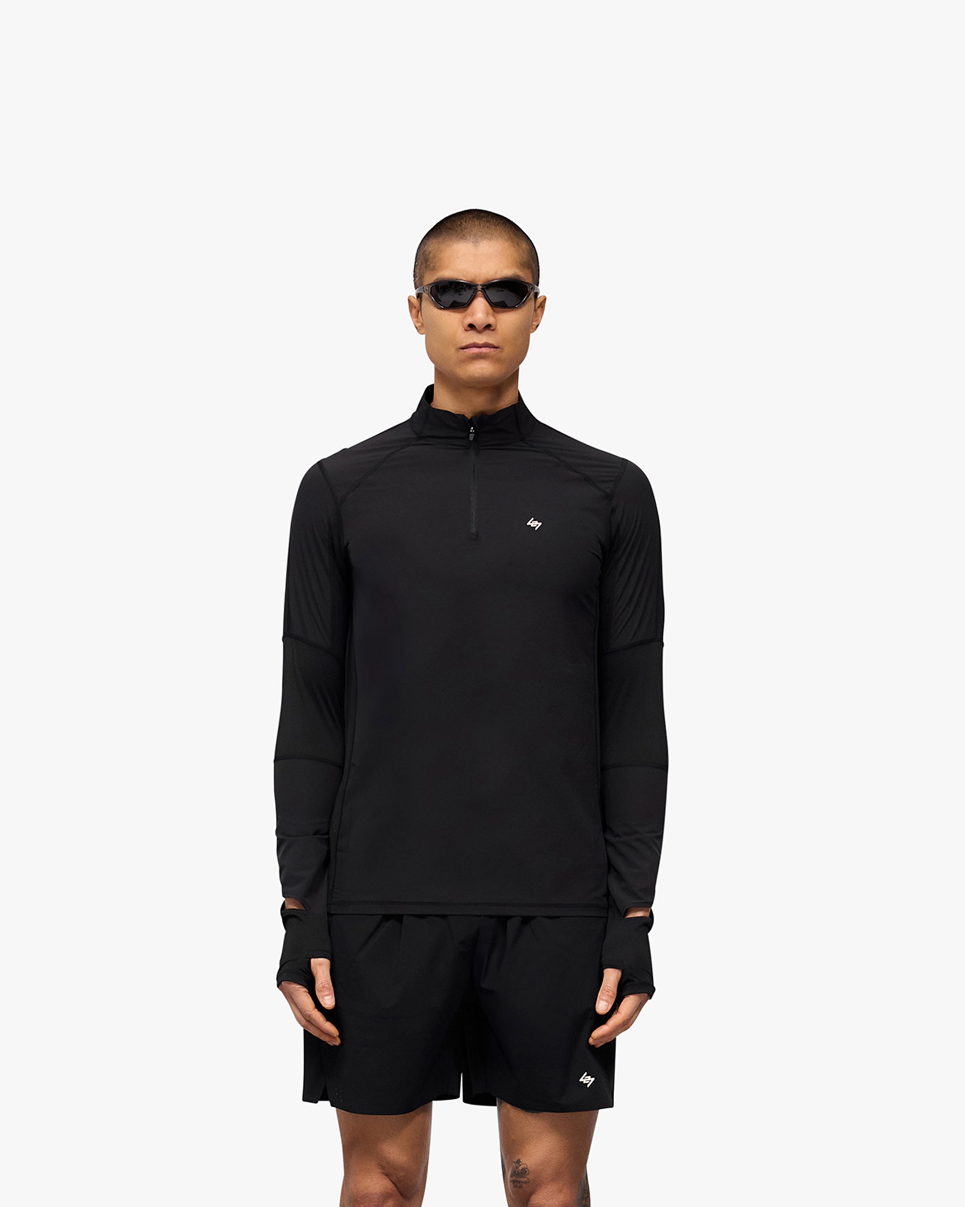 Man wearing a black quarter zip top on a plain white background | 247 Run Quarter Zip in Jet Black | Performance outerwear with mesh panels and thumb holes | 247 Outerwear | Represent Clo