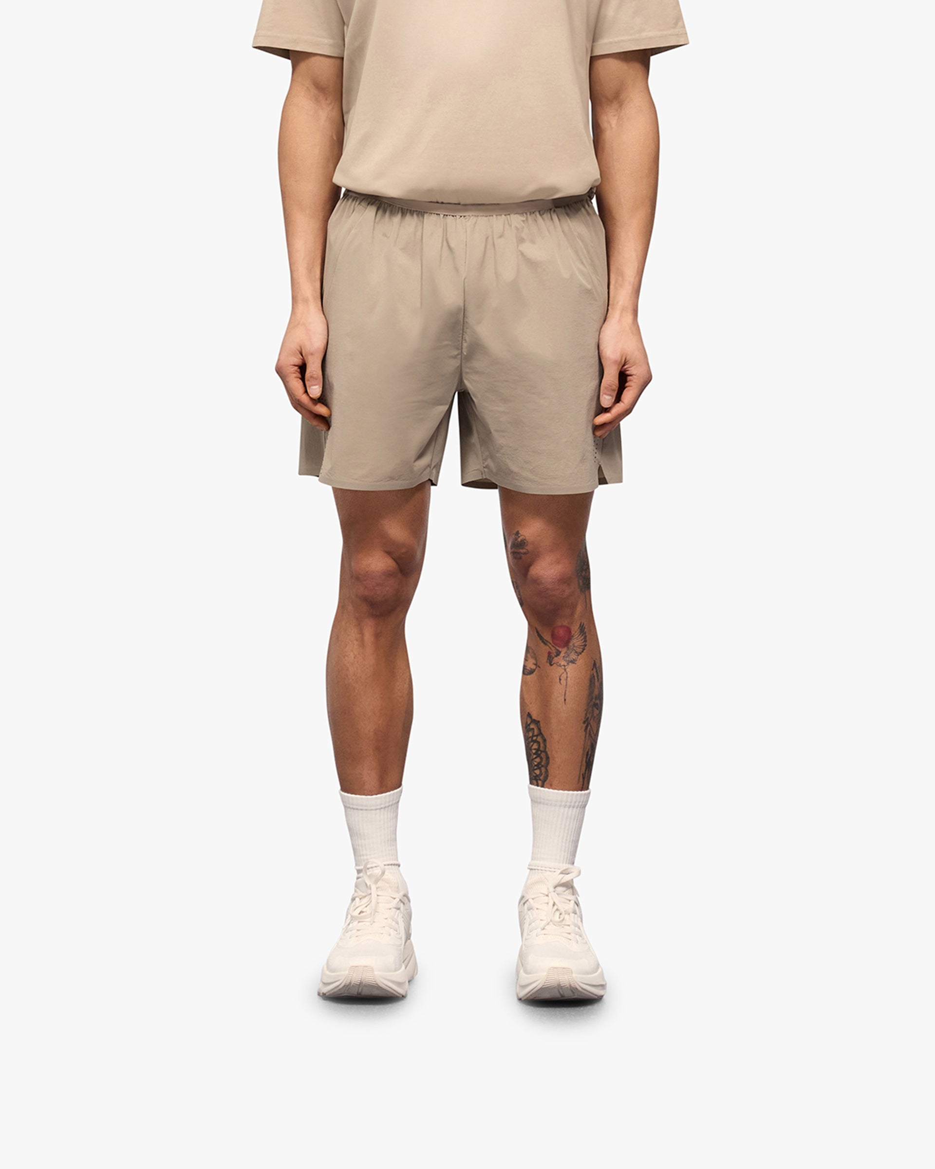 Man wearing grey shorts on a plain white background | 247 Training Shorts in Pebble | Nylon blend shorts with zip pockets and perforation detailing | 247 Shorts | Represent Clo