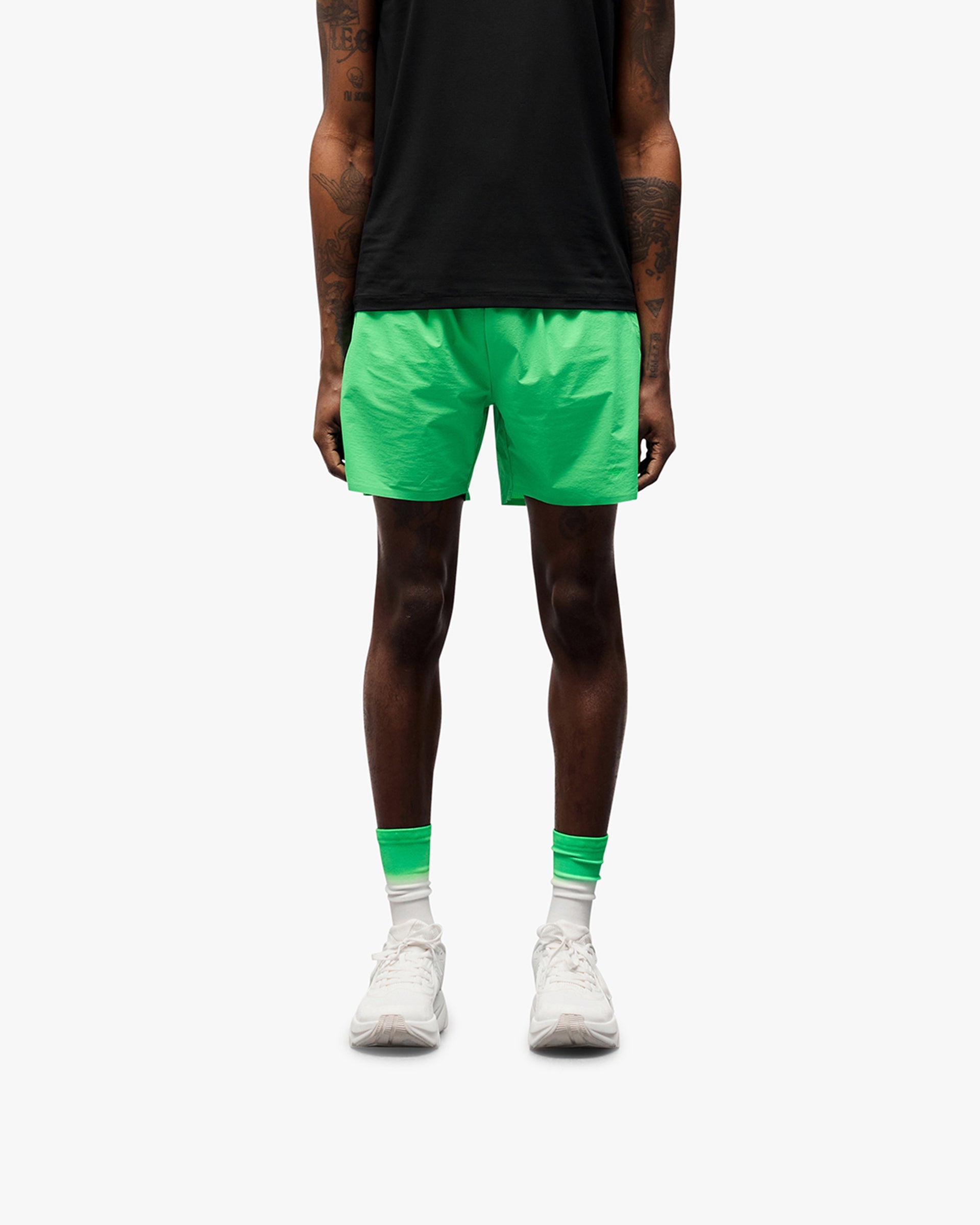 Man wearing green training shorts on a plain white background | 247 Training Shorts in Speed Green | Shorts with perforation detailing and zip pockets | 247 Shorts | Represent Clo