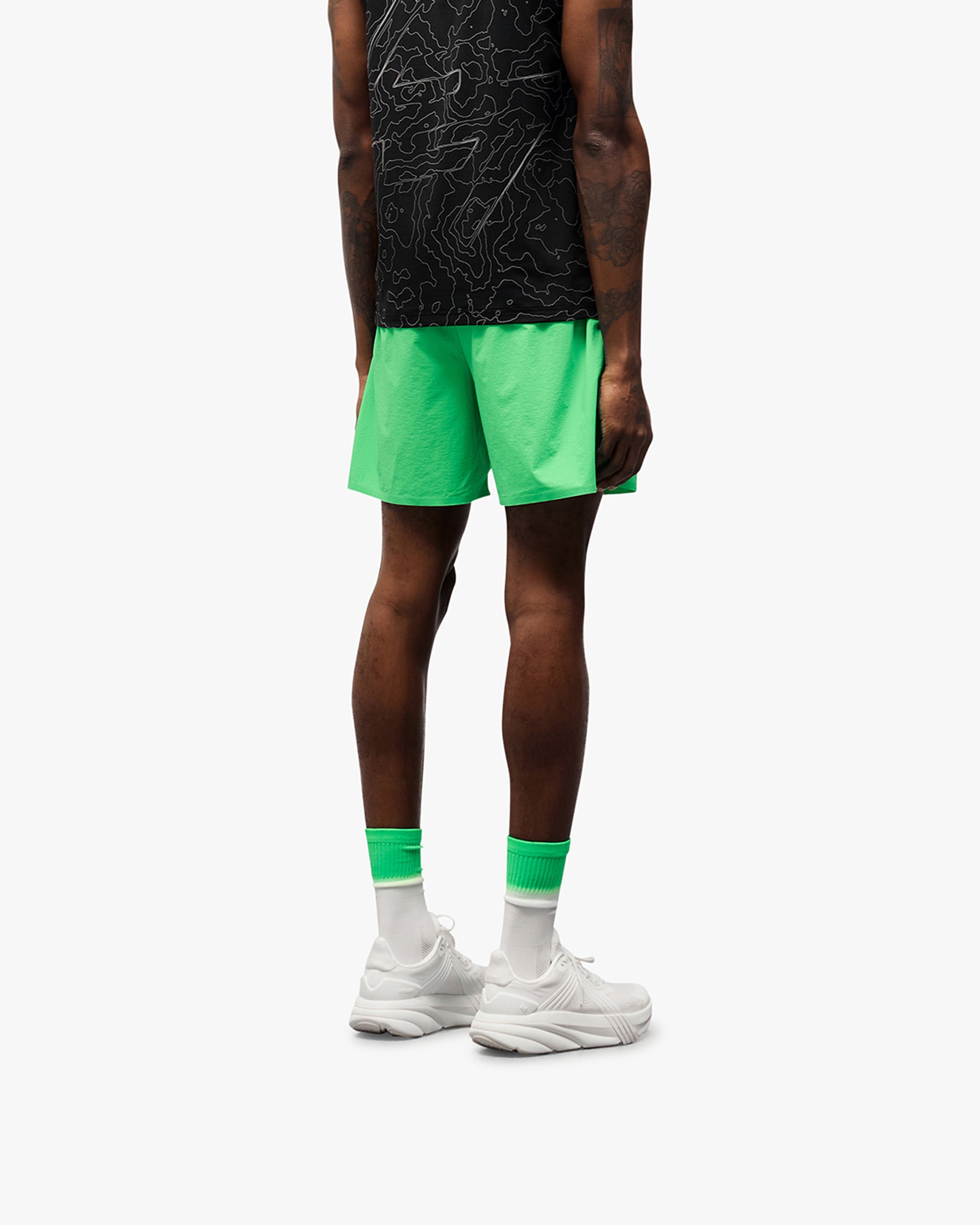 Man wearing green shorts on a plain white background | 247 Training Shorts in Speed Green | Shorts with perforation detailing for breathability | 247 Shorts | Represent Clo