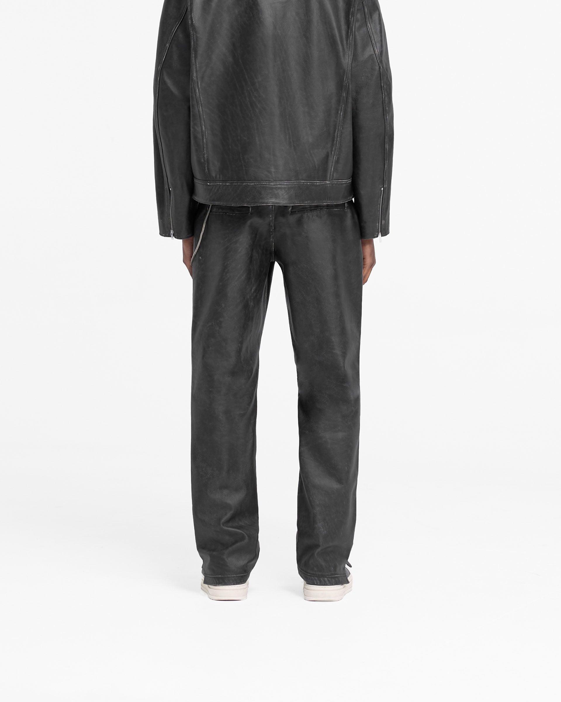 Man wearing distressed black leather pants on a plain white background | Distressed Leather Pant in Black | Leather pants with straight leg fit and knee darts | FW24 Pants | Represent Clo