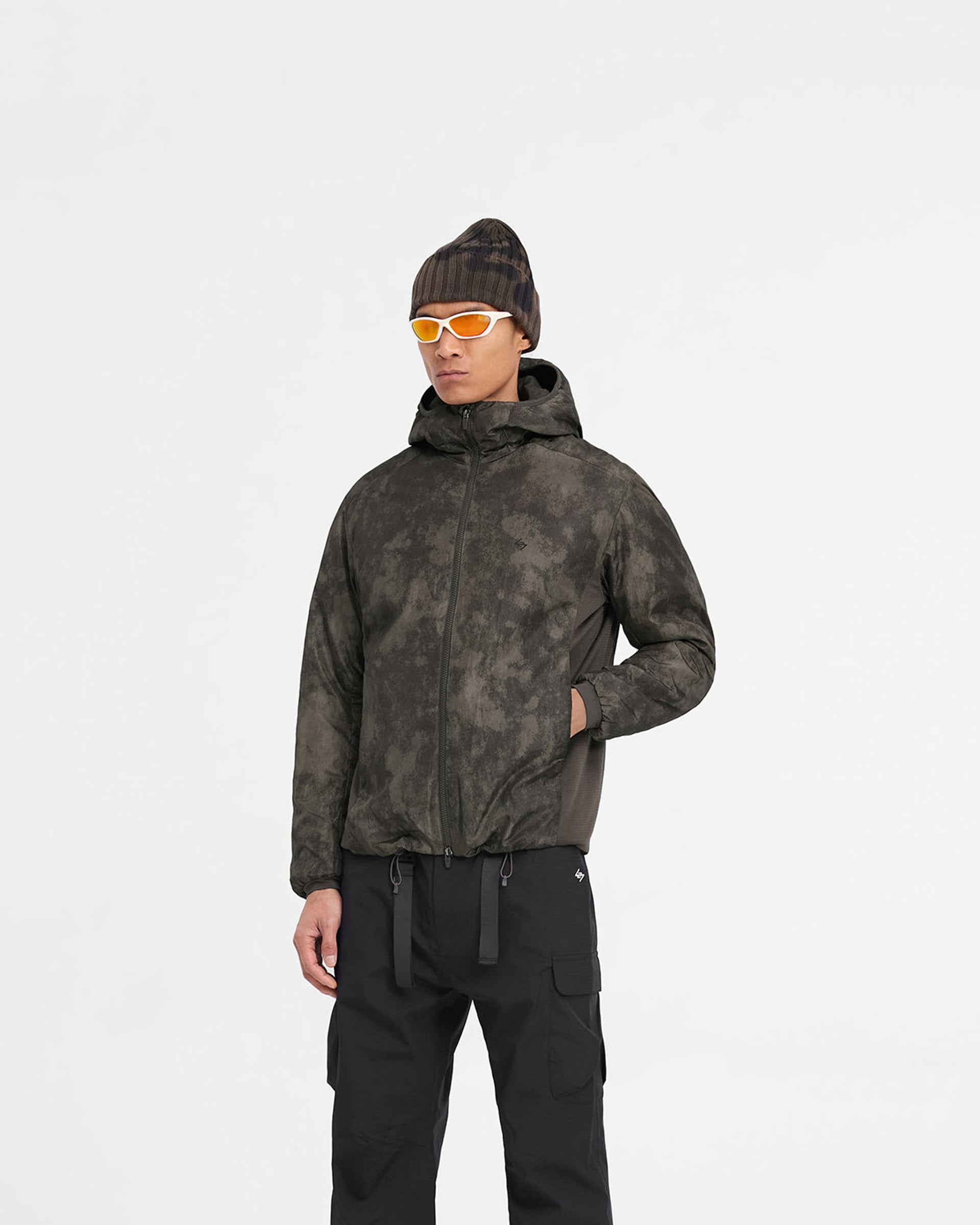Man wearing a brown insulated jacket on a plain white background | Team 247 Insulated Jacket in Terrain | Insulated jacket with water repellent and adjustable hood | 247 Outerwear | Represent Clo