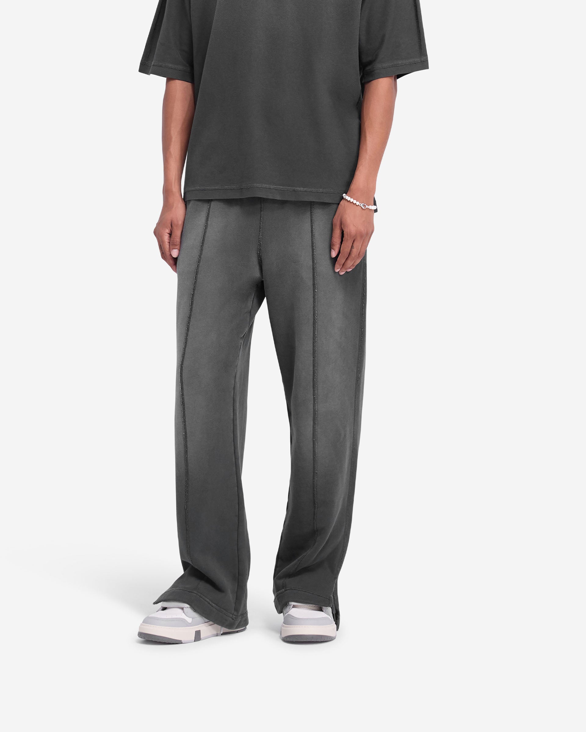 Man wearing wide-leg black sweatpants on a plain white background | Stepped Hem Sweatpants in Stained Black | Sweatpants with elasticated waistband and stepped hem | FW24 Pants | Represent Clo