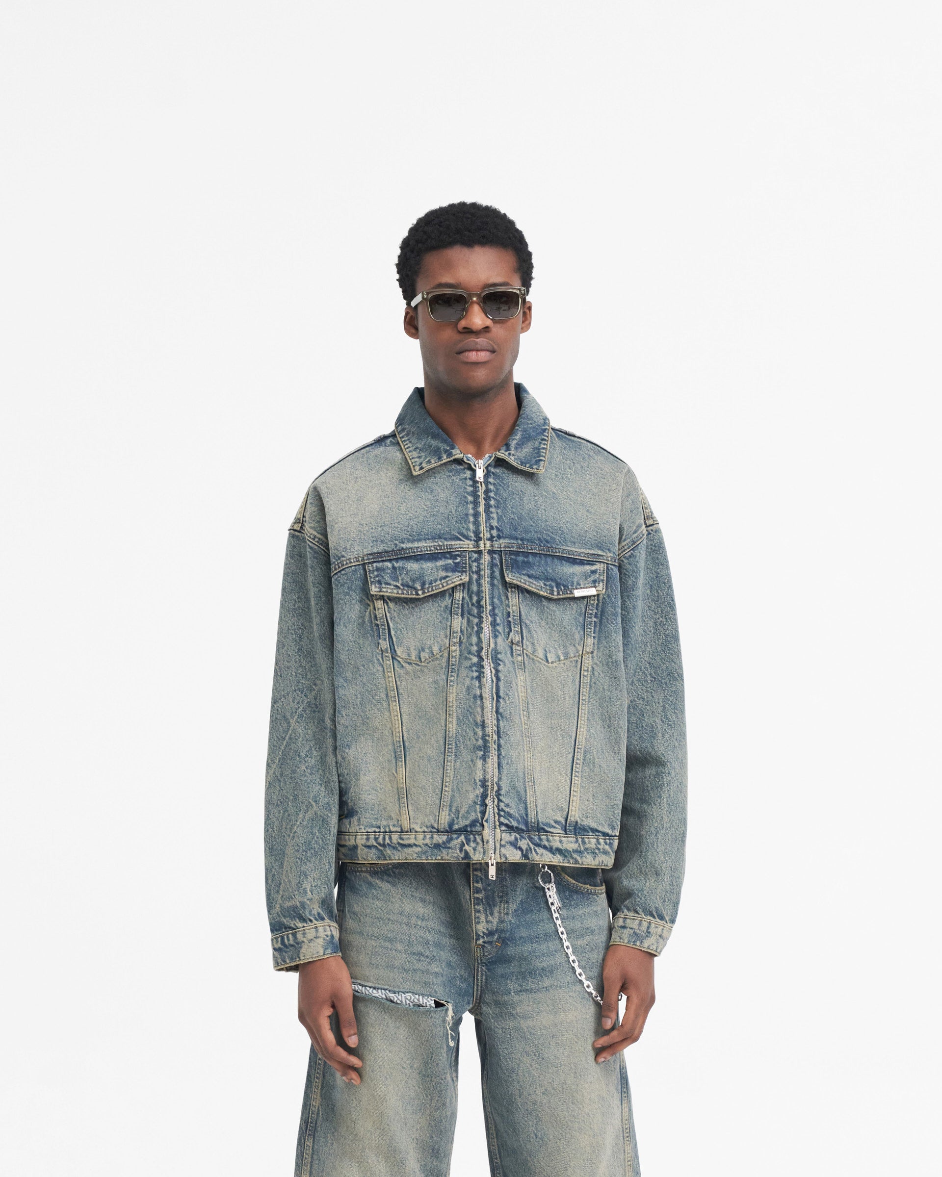 Man wearing a denim jacket in blue on a plain white background | R4 Denim Jacket in Blue Cream | Slightly oversized denim jacket with double zip closure | SS24 Denim | Represent Clo