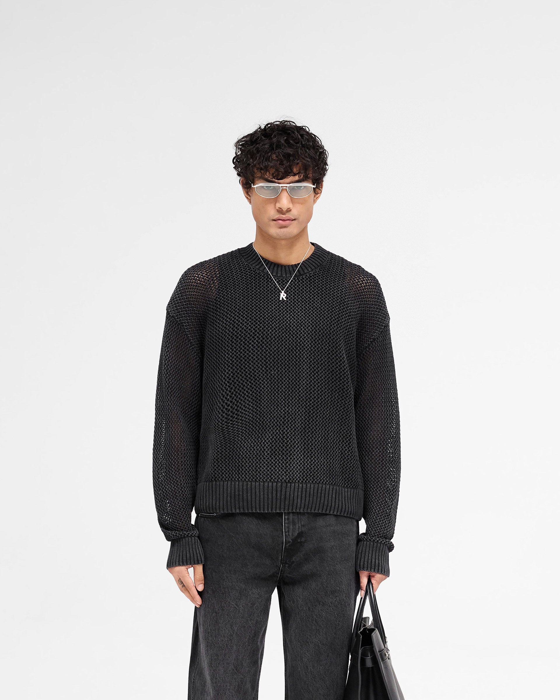Man wearing a black knit sweater on a plain white background | Open Gauge Knit Sweater in Jet Black | Slightly oversized knitwear with ribbed details | SS25 Knitwear | Represent Clo