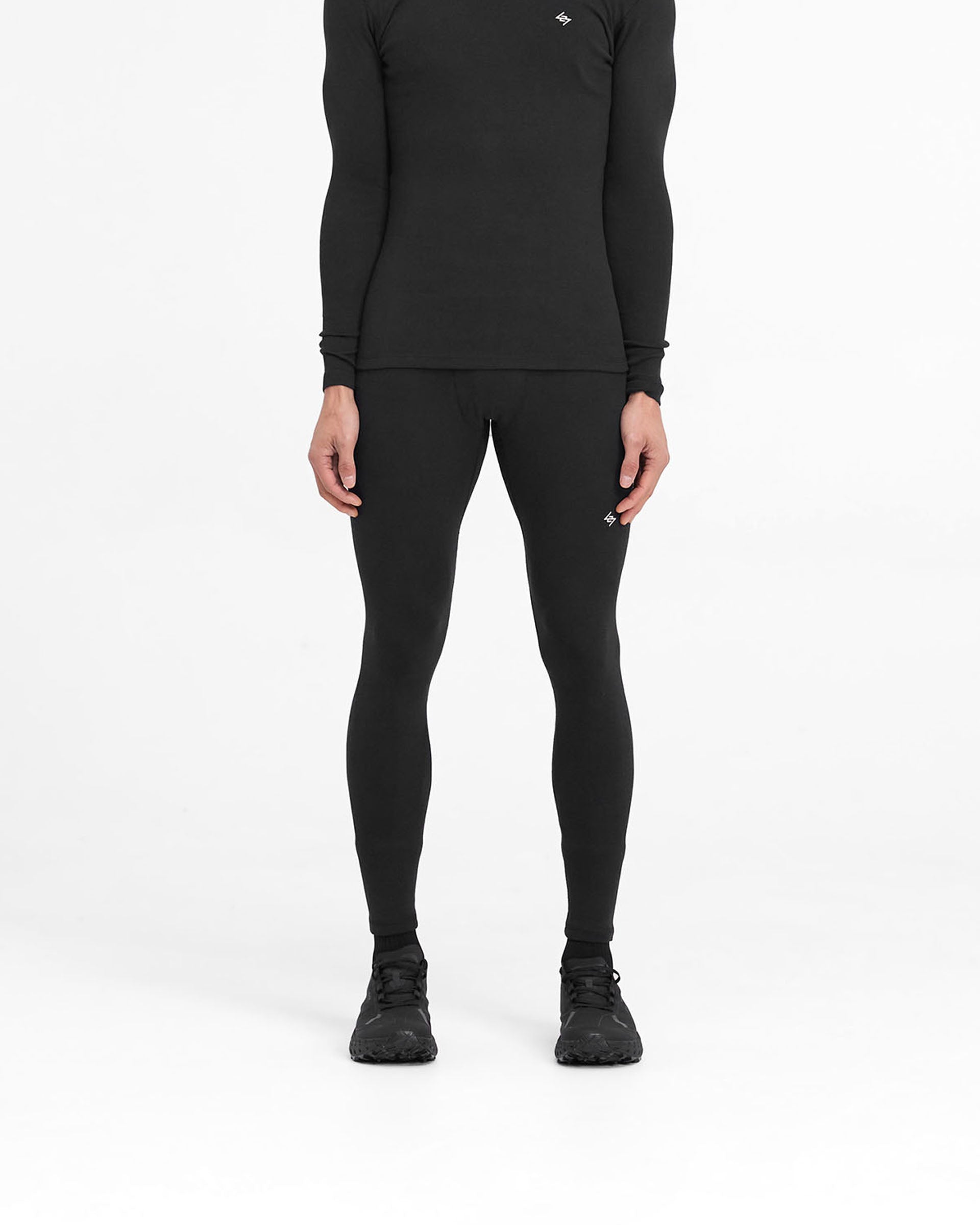 Man wearing black ribbed leggings on a plain white background | 247 Ribbed Legging in Black | Close fit ribbed leggings with embroidered 247 logo | 247 Pants | Represent Clo