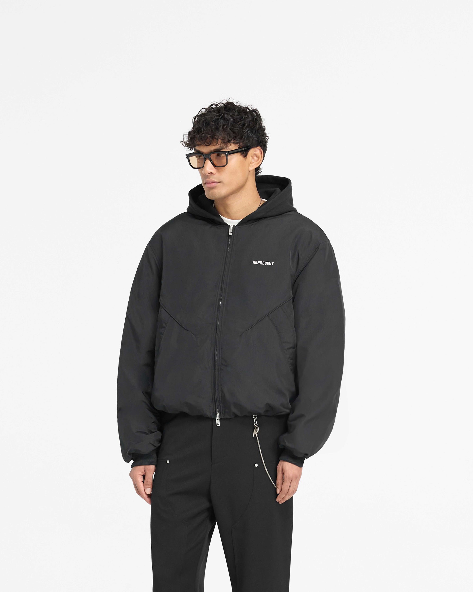 Back product image of a mens black bomber jacket on a plain white background | Nylon Hooded Bomber Jacket in Black | Oversized bomber with adjustable bungee cord and welt pockets | PRE SS25 Outerwear | Represent Clo