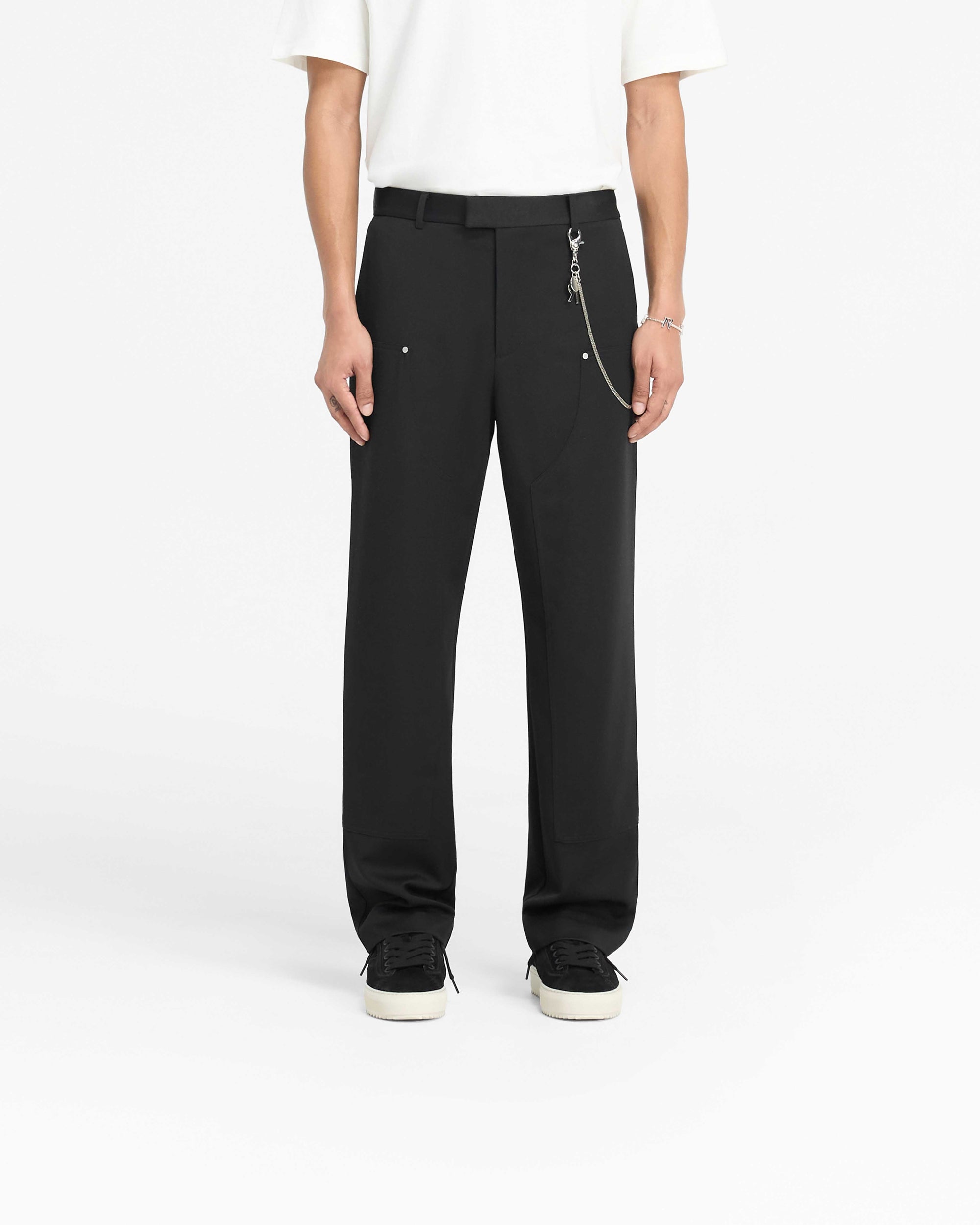 Man wearing black pants on a plain white background | Smart Utility Pant in Jet Black | Straight leg pants with a fixed waistband and metal rivets | PRE SS25 Pants | Represent Clo