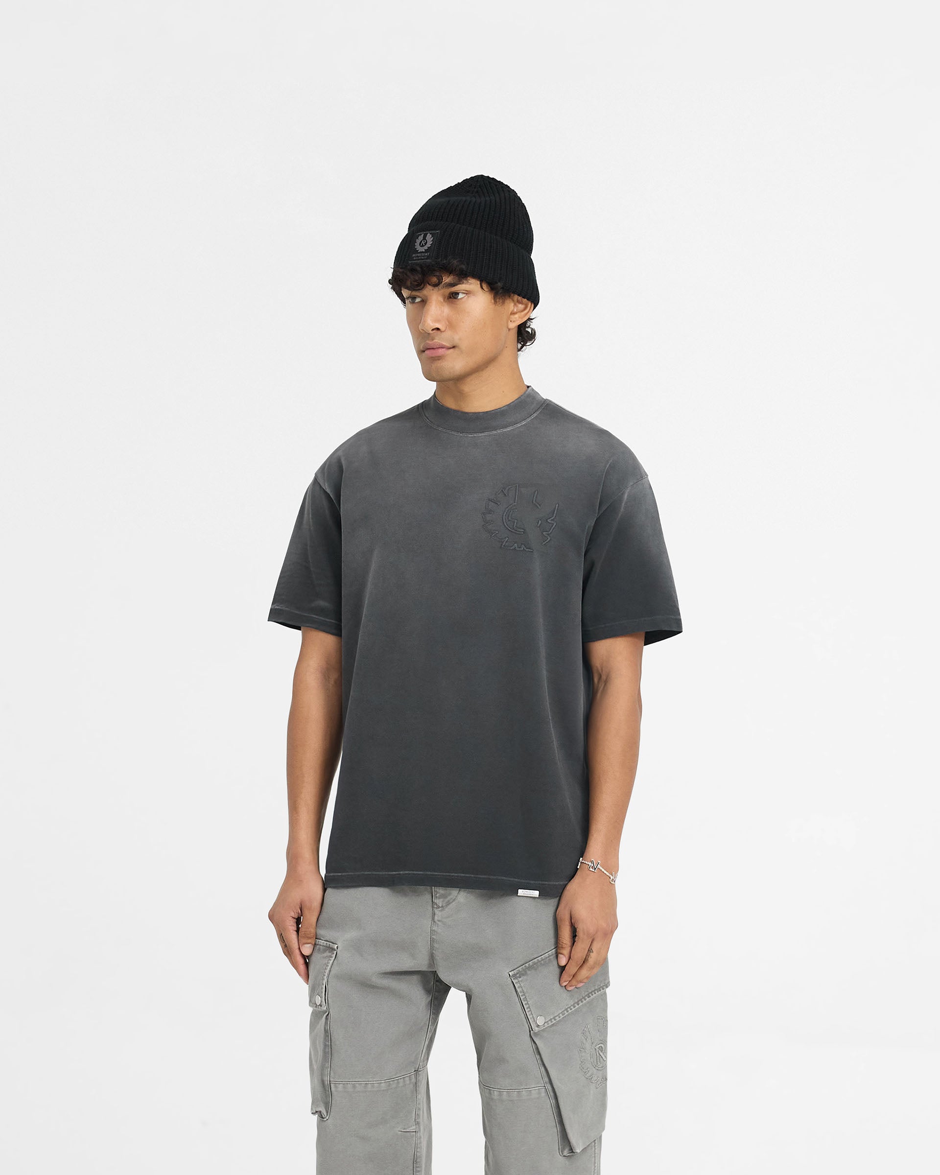 Man wearing a black t-shirt on a plain white background | Represent X Belstaff Outline Phoenix T-Shirt in Shadow | Oversized medium weight t-shirt with embroidered logos | Exclusives T-Shirts | Represent Clo