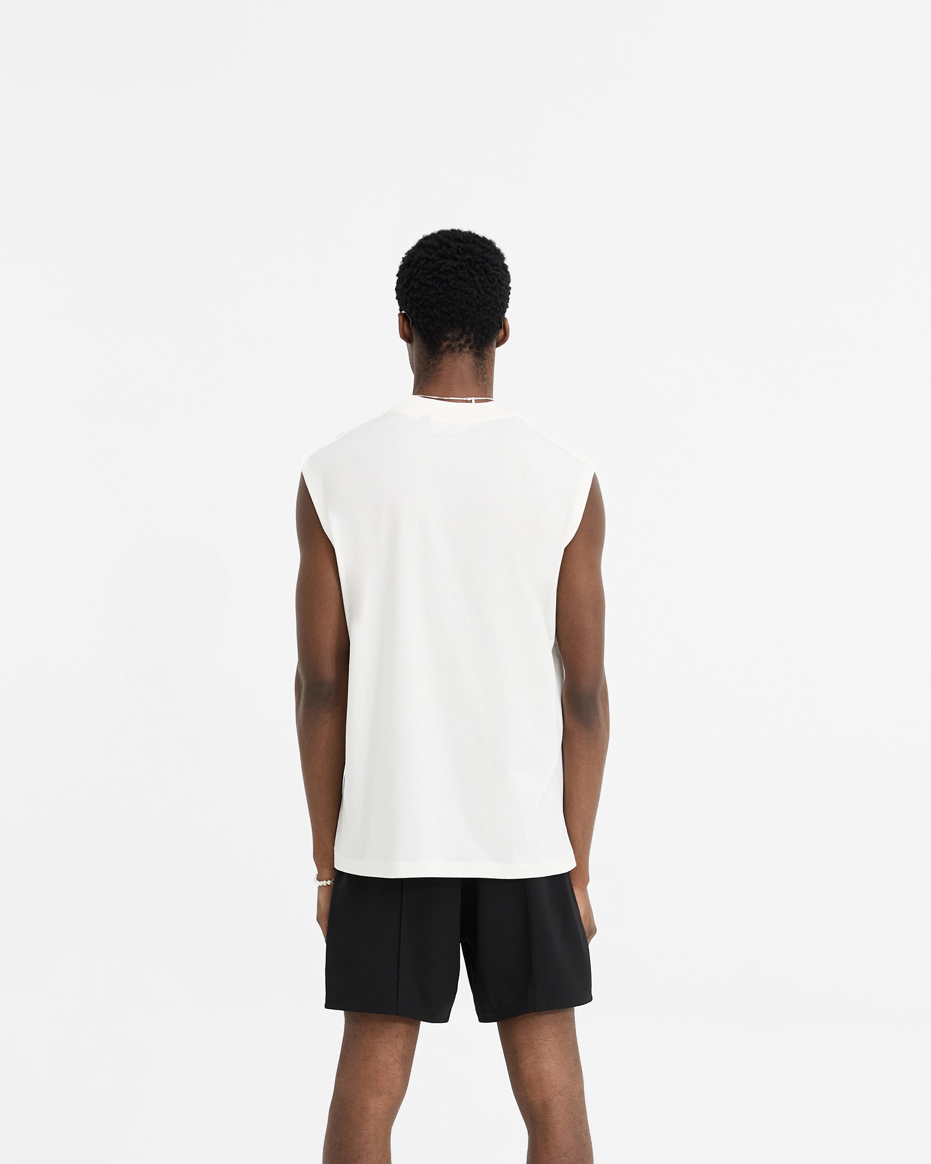 Man wearing an oversized white tank top on a plain white background | Initial Boxy Tank in Flat White | Boxy cropped tank with ribbed collar | Initial T-Shirts | Represent Clo