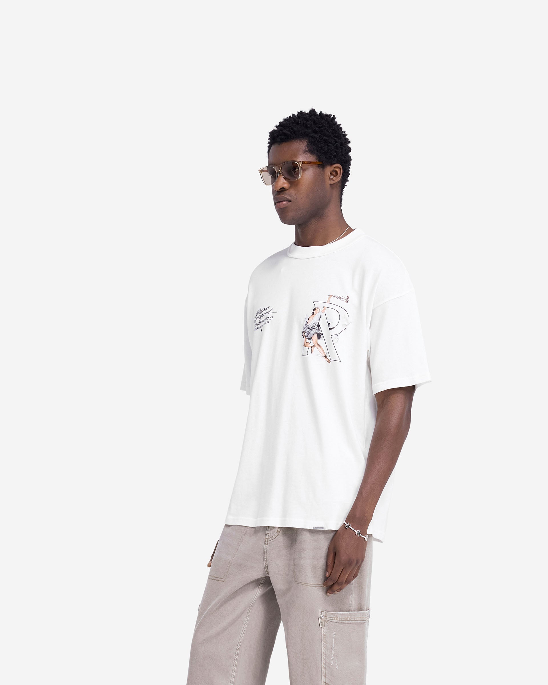 Man wearing an oversized white t-shirt with graphic print on a plain white background | Hermes T-Shirt in Flat White | Oversized t-shirt with metal bar logo | FW24 T-Shirts | Represent Clo