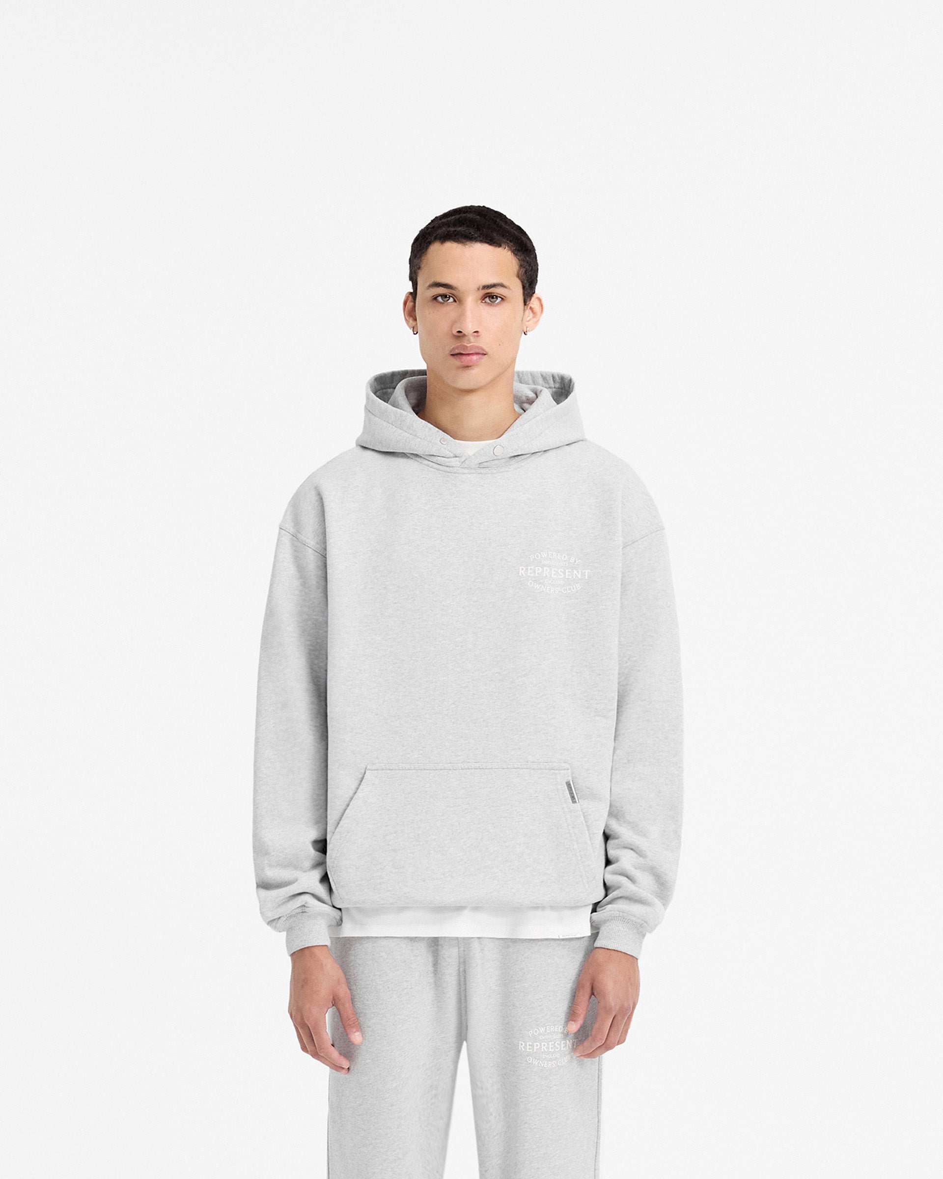 Man wearing an ash grey hoodie on a plain white background | Represent Owners Club Stamp Hoodie in Ash Grey | Oversized fit hoodie with high build branding | Owners Club Hoodies | Represent Clo