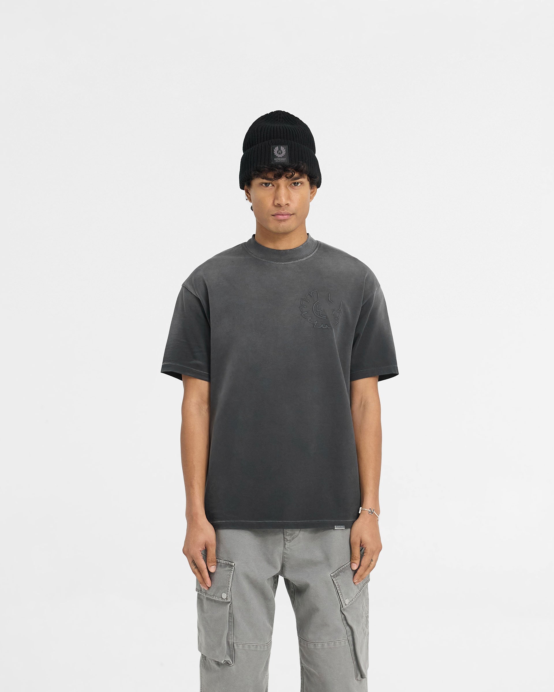 Man wearing a black t-shirt with logo detailing on a plain white background | Represent X Belstaff Outline Phoenix T-Shirt in Shadow | Oversized t-shirt with embroidered logos | Exclusives T-Shirts | Represent Clo