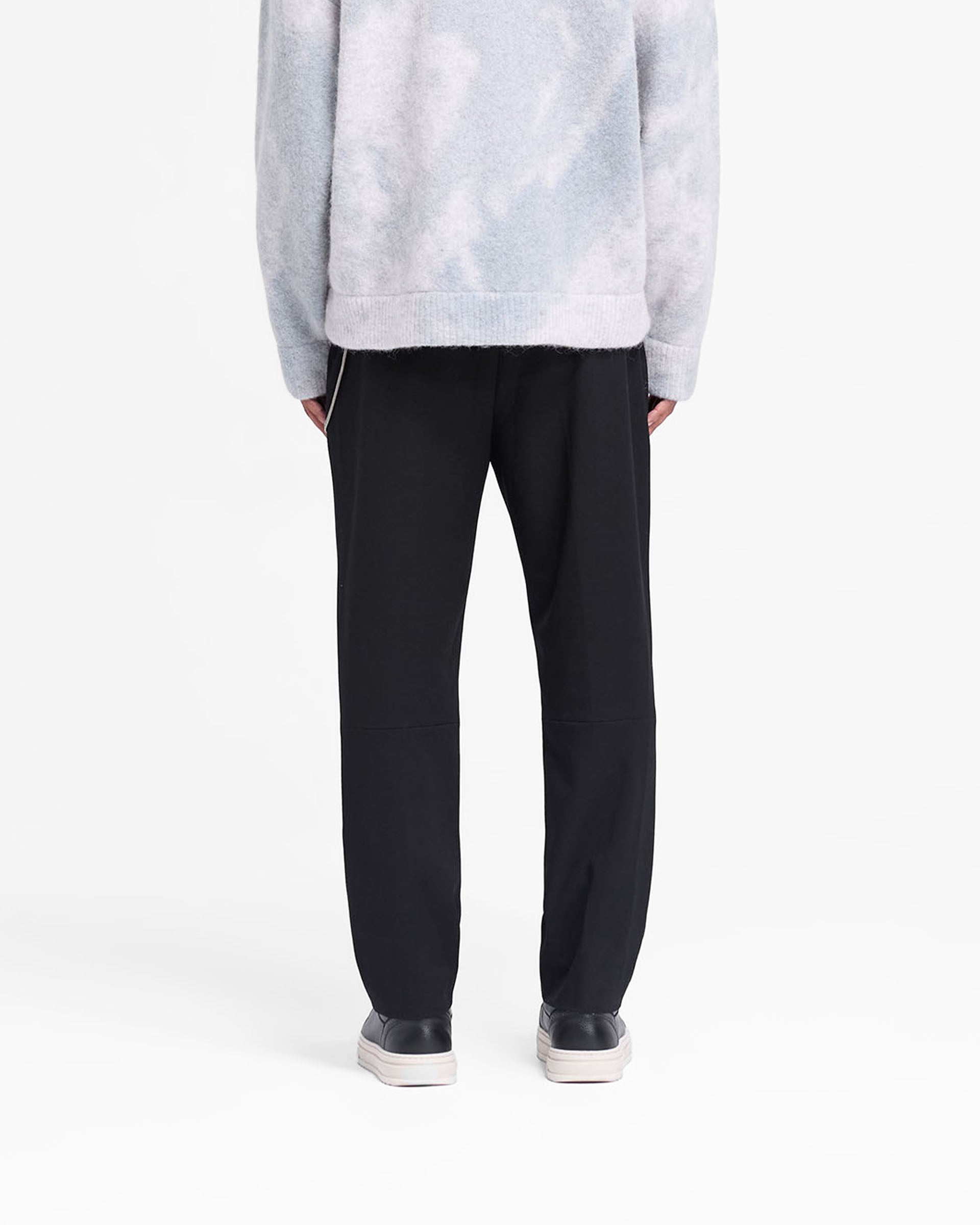 Man wearing black pants on a plain white background | Smoking Pant in Black | Smart slim silhouette pants with cropped length and fixed waistband | FW24 Pants | Represent Clo