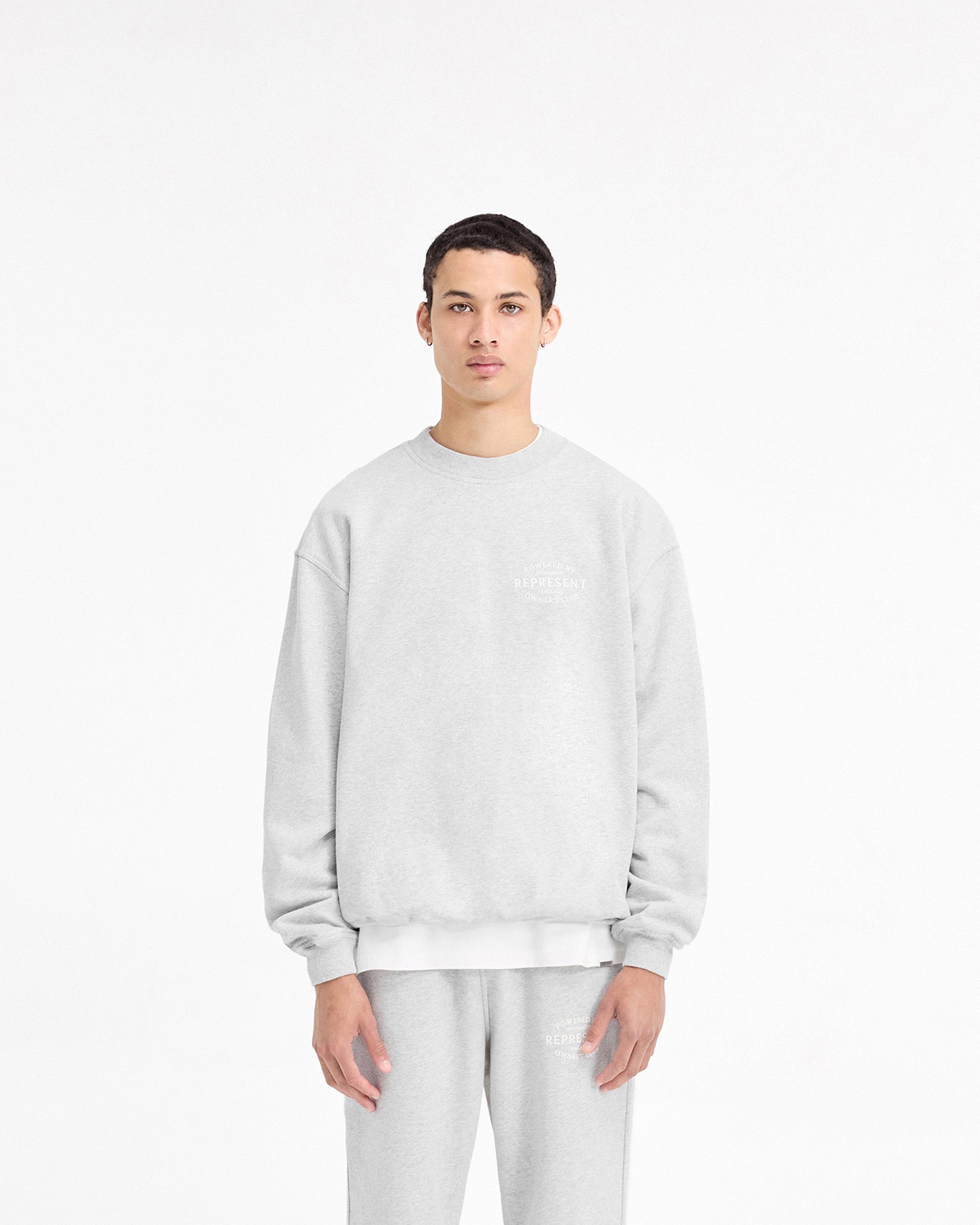 Man wearing a grey sweater on a plain white background | Represent Owners Club Stamp Sweater in Ash Grey | Heavy weight jersey cotton sweater with ribbed collar | Owners Club Sweaters | Represent Clo