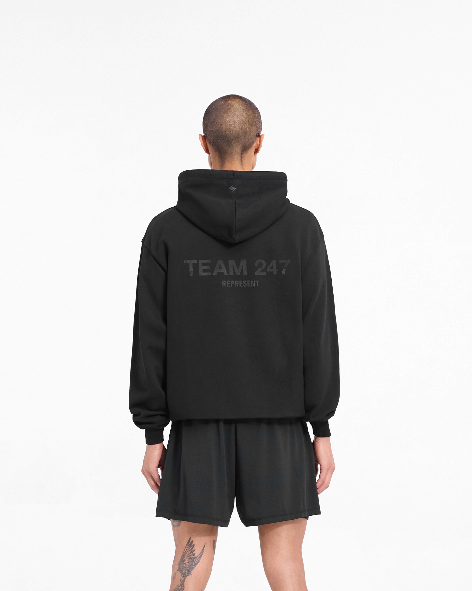 Man wearing an oversized black hoodie on a plain white background | Team 247 Oversized Hoodie in Matte Black | Hoodie with ribbed cuffs and hem | 247 Hoodies | Represent Clo