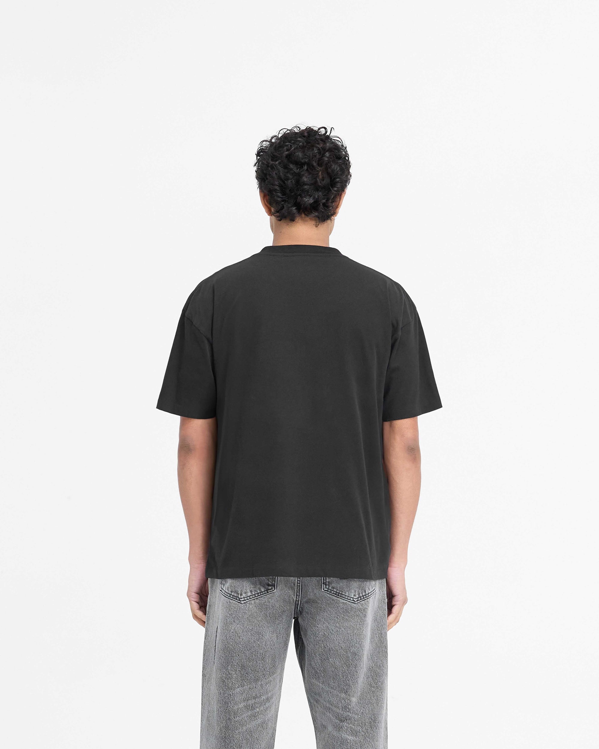 Man wearing a black t-shirt on a plain white background | Serif Logo T-Shirt in Jet Black | Slightly oversized t-shirt with embroidered branding | PRE SS25 T-Shirts | Represent Clo