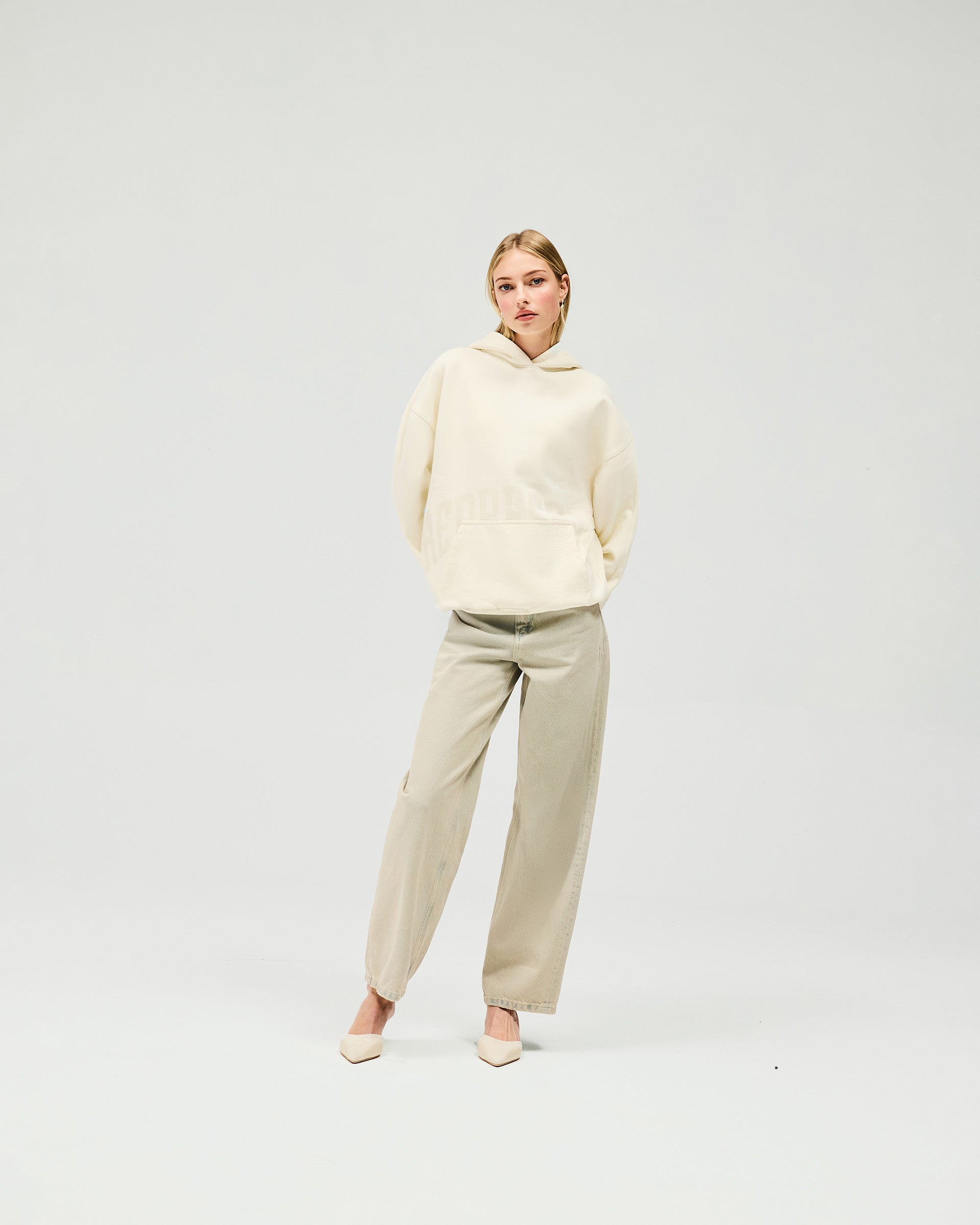 Woman wearing an oversized cream hoodie on a plain white background | Boyfriend Graphic Hoodie in Cream | Relaxed fit mid weight brushed fleece hoodie | Womens SS25 Hoodies | Represent Clo