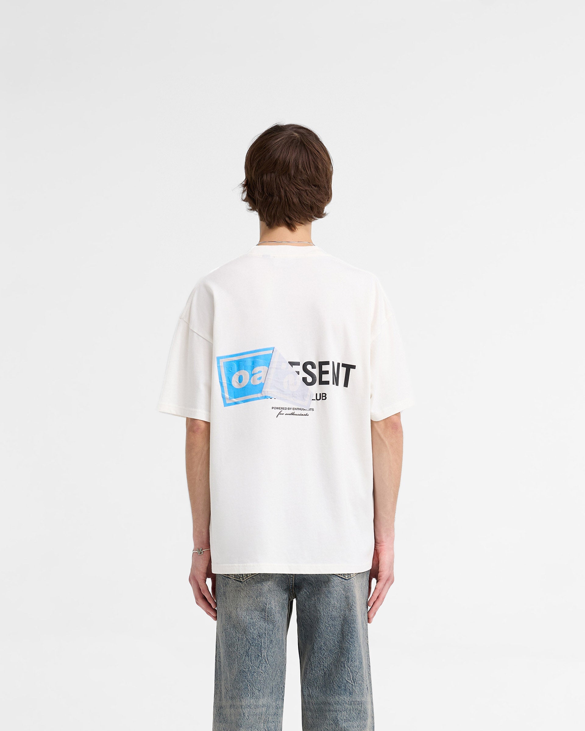 Man wearing a white t-shirt with graphic print on a plain white background | Represent X Oasis Owners Club T-Shirt in Flat White | Oversized fit t-shirt with Oasis artwork and Owners Club branding | FW24 T-Shirts | Represent Clo