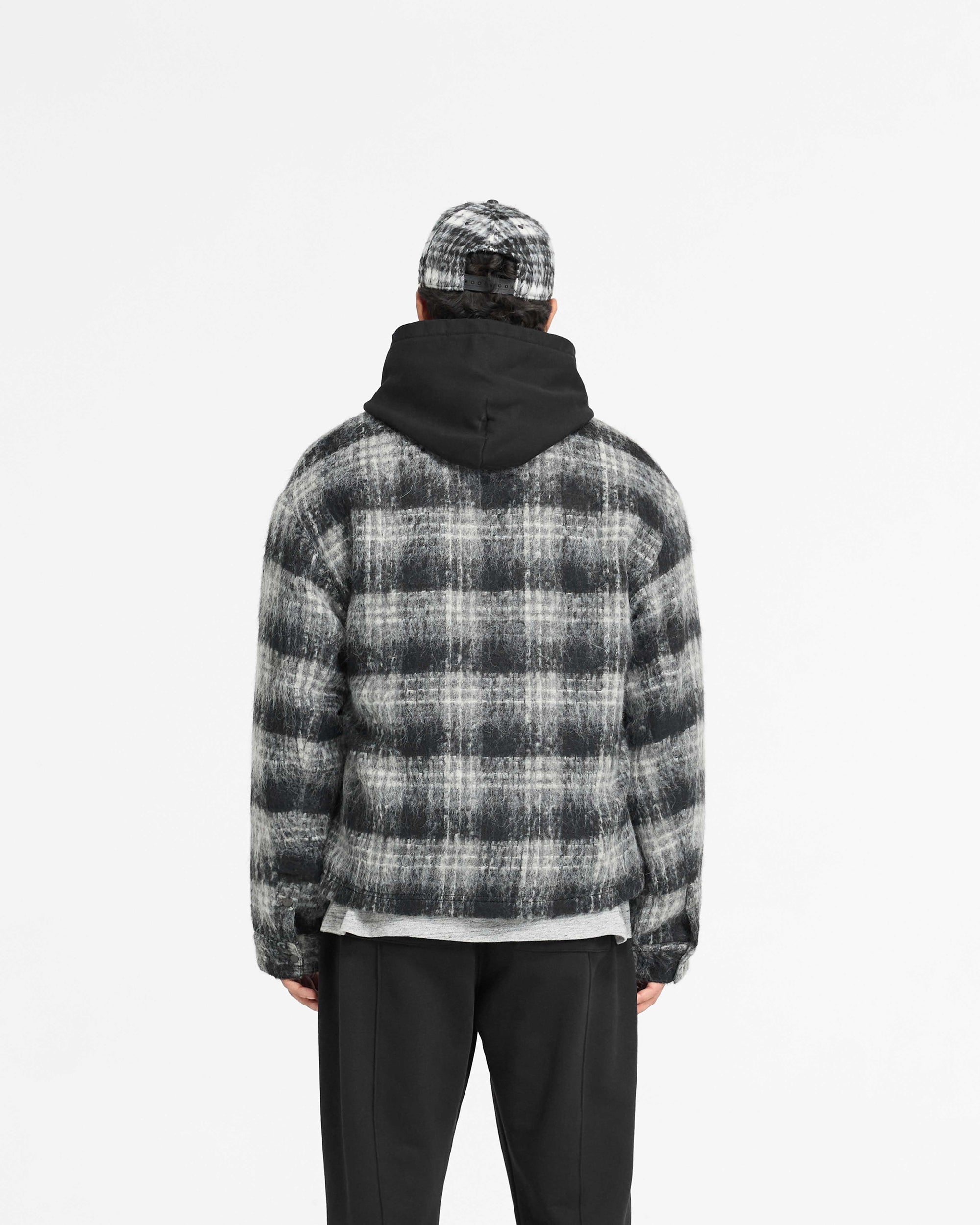 Man wearing a black flannel check overshirt on a plain white background | Flannel Check Overshirt in Jet Black | Oversized shirt with faux leather collar and double zip closure | PRE SS25 Shirts | Represent Clo