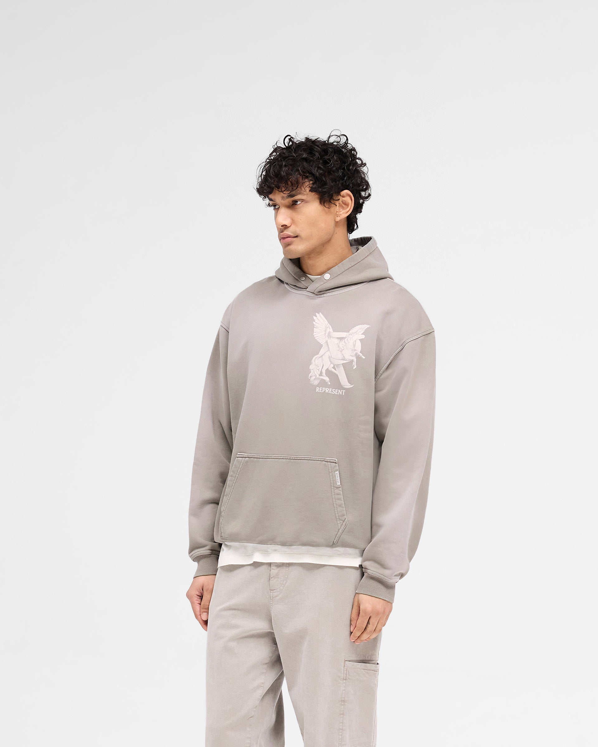 Man wearing a grey oversized hoodie on a plain white background | Elegance In Motion Hoodie in Thunder | Heavyweight jersey hoodie with graphic and popper fastening | SS25 Hoodies | Represent Clo
