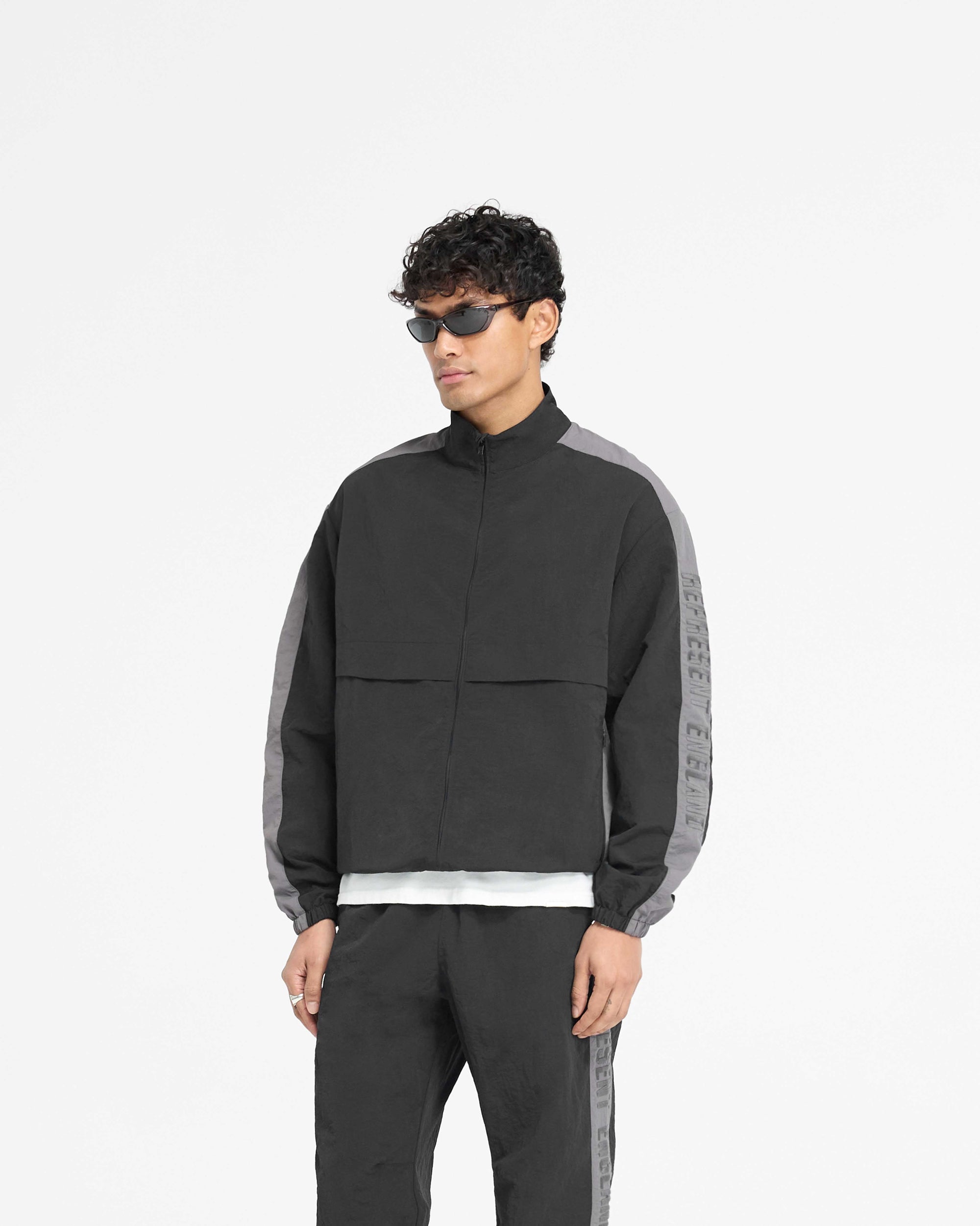 Back product image of a mens black nylon jacket on a plain white background | Nylon Track Jacket in Black | Slightly oversized track jacket with storm flaps and crinkle texture | PRE SS25 Outerwear | Represent Clo