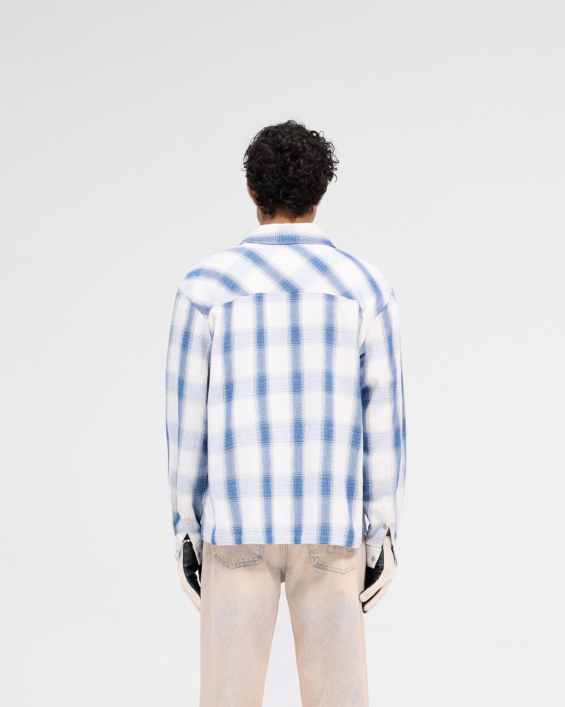 Man wearing a mid blue flannel shirt on a plain white background | Season Flannel Shirt in Mid Blue | Textured flannel shirt with front flap pockets | SS25 Shirts | Represent Clo
