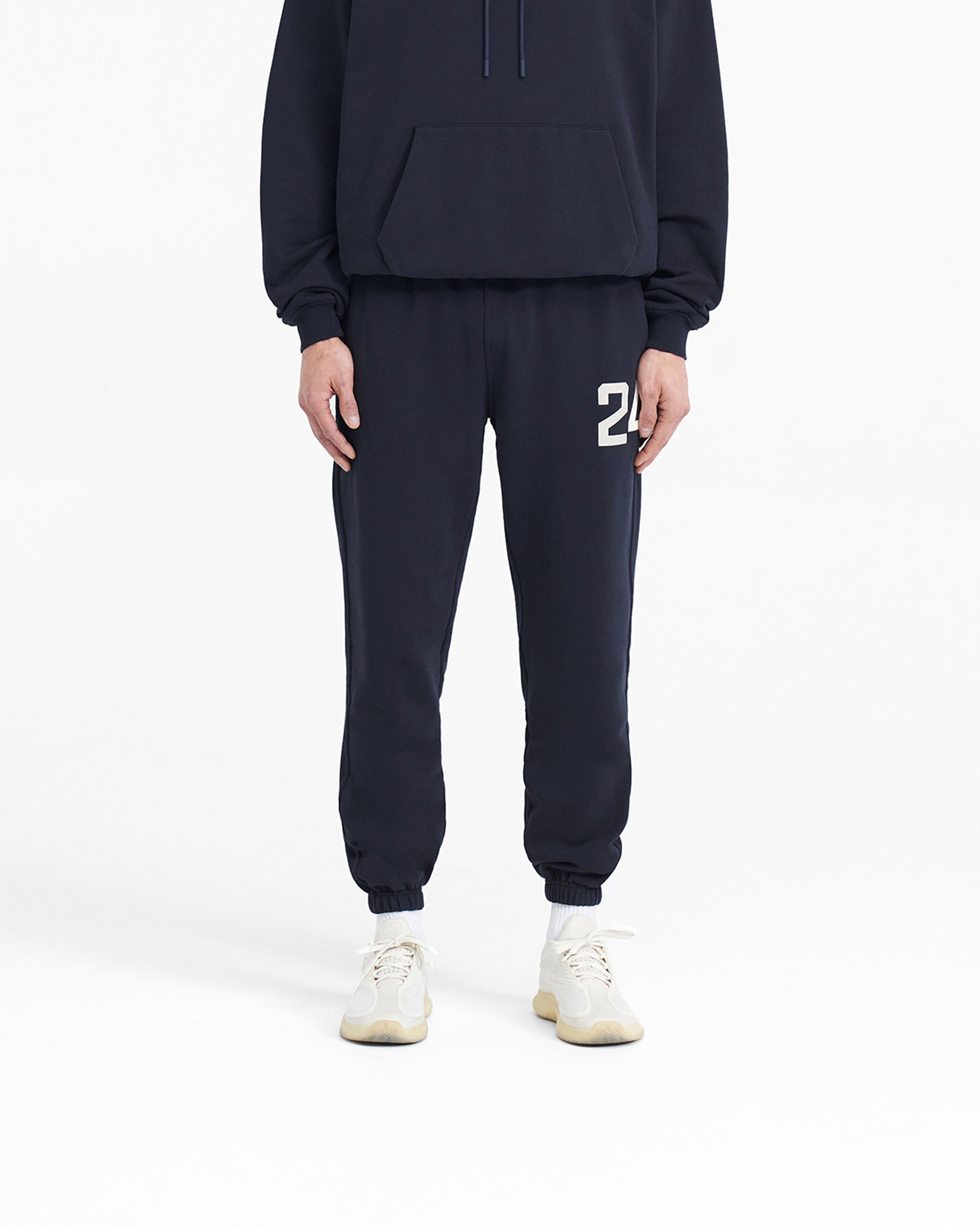 Man wearing navy sweatpants on a plain white background | 247 Sweatpant in Navy | Sweatpants with elasticated cuffs and drawcord waistband | 247 Pants | Represent Clo