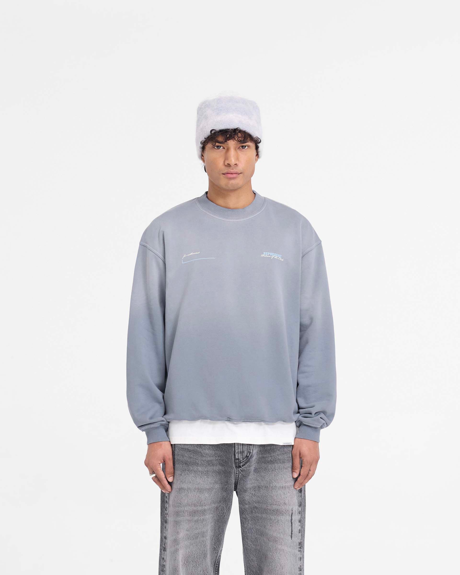 Man wearing a grey oversized sweater on a plain white background | Patron Of The Club Sweater in Washed Grey | Oversized sweater with Patron of the Club print | Patrons Sweaters | Represent Clo