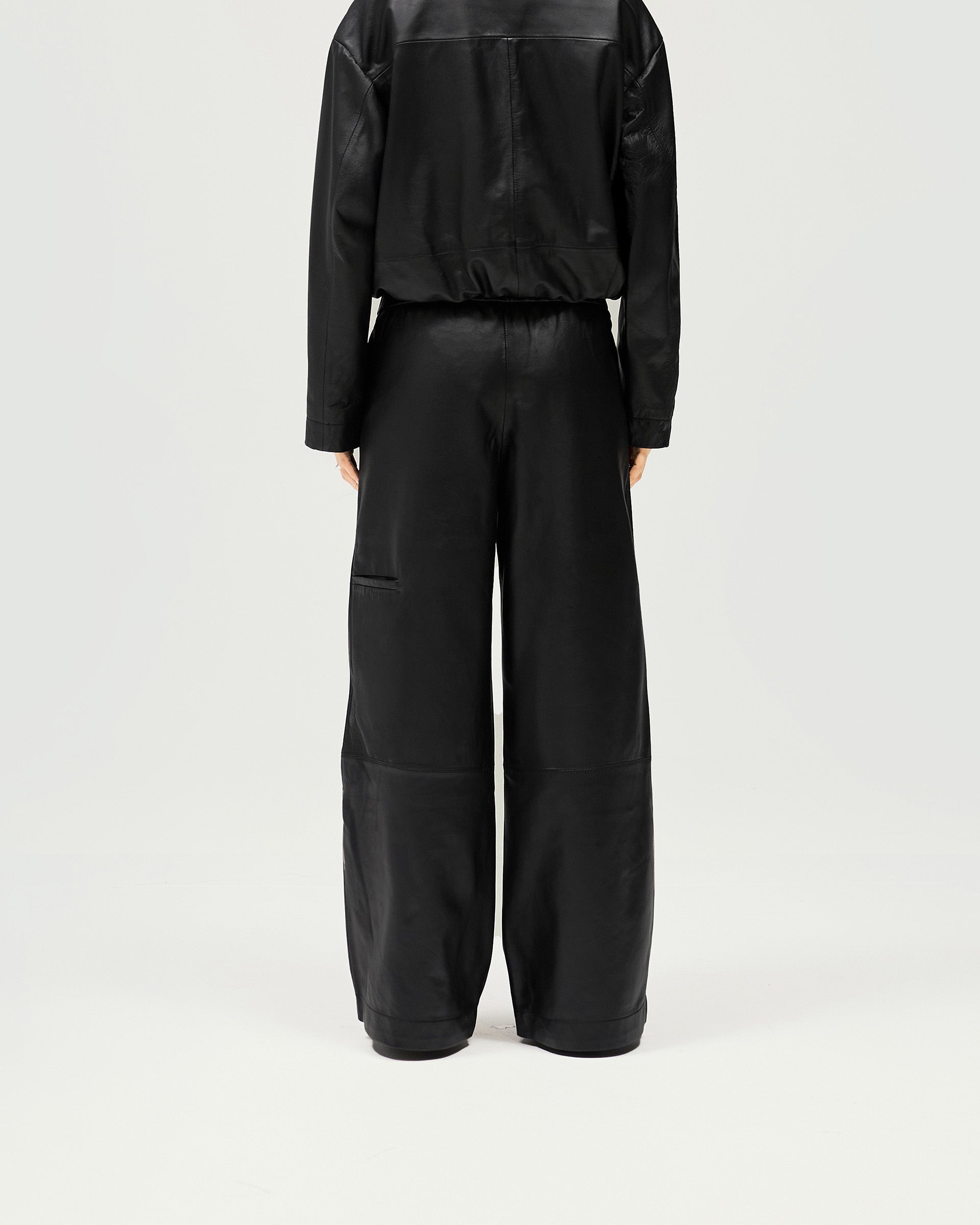 Back product image of womens black leather pants on a plain white background | Fuel Trouser in Jet Black | Track pant style with wide leg and elasticated waist | Womens SS25 Bottoms | Represent Clo