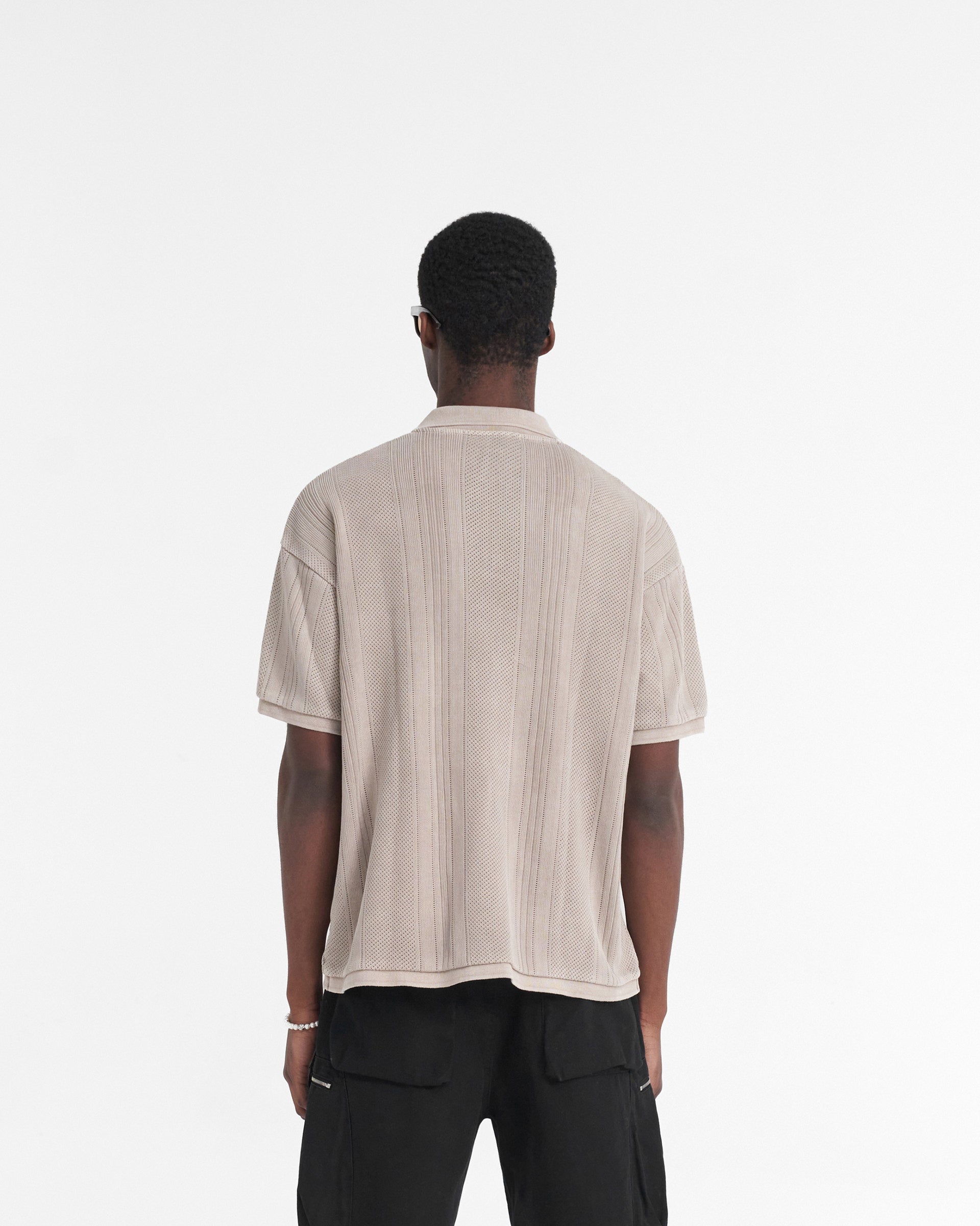 Man wearing a cream polo shirt on a plain white background | Open Stitch Polo in Cashmere | Polo shirt with open collar and embroidered logo | SS24 T-Shirts | Represent Clo