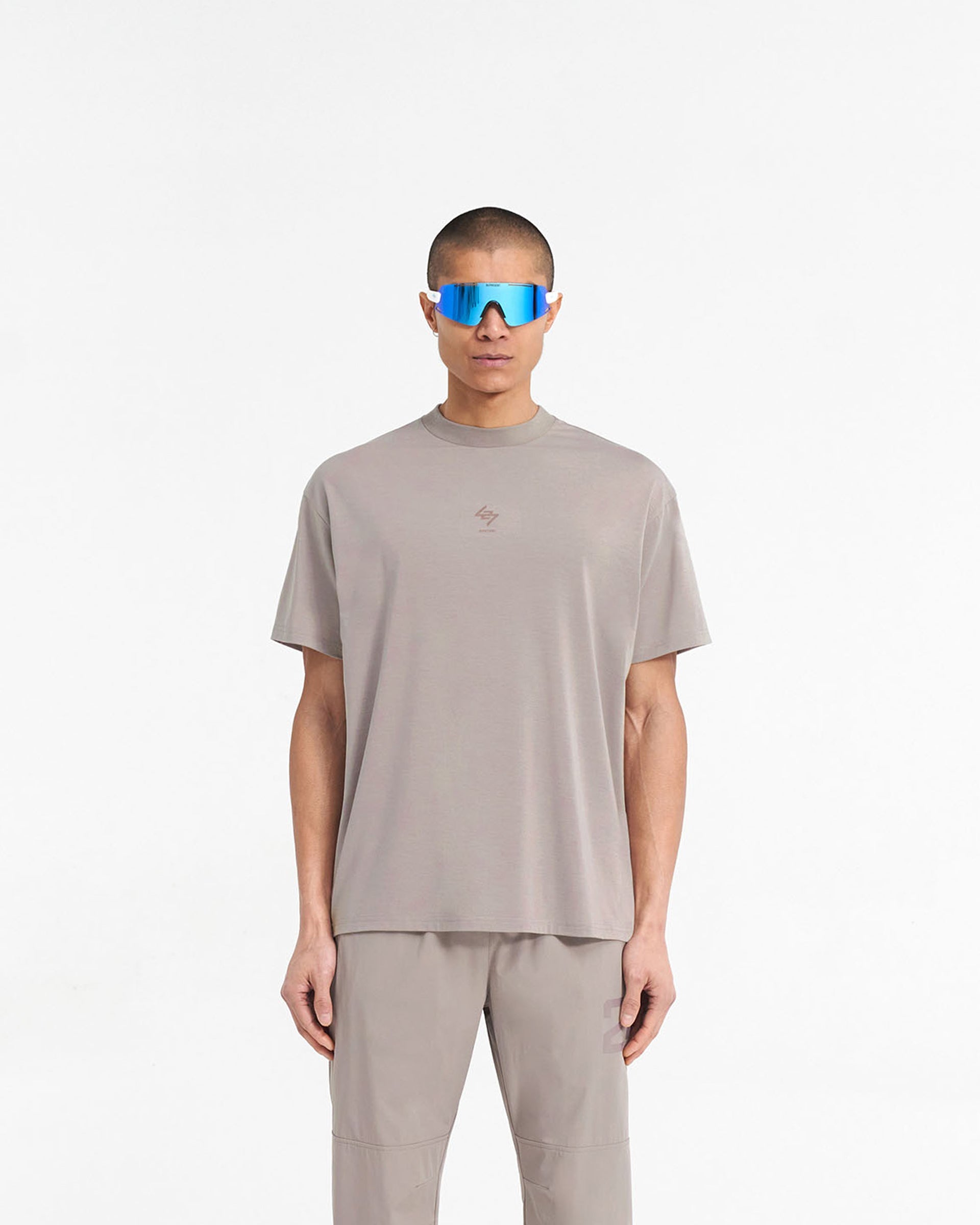 Man wearing an oversized grey t-shirt on a plain white background | 247 Oversized T-Shirt in Cinder | Gym t-shirt with 4-way stretch and quick dry fabric | 247 T-Shirts | Represent Clo