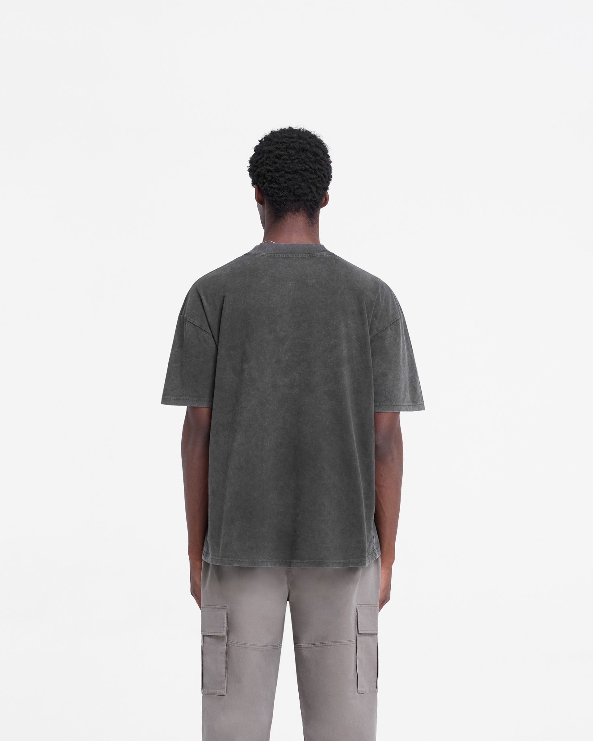 Man wearing a vintage black t-shirt on a plain white background | Rep Applique T-Shirt in Vintage Black | Slightly oversized t-shirt with distressed applique Rep logo | FW24 T-Shirts | Represent Clo