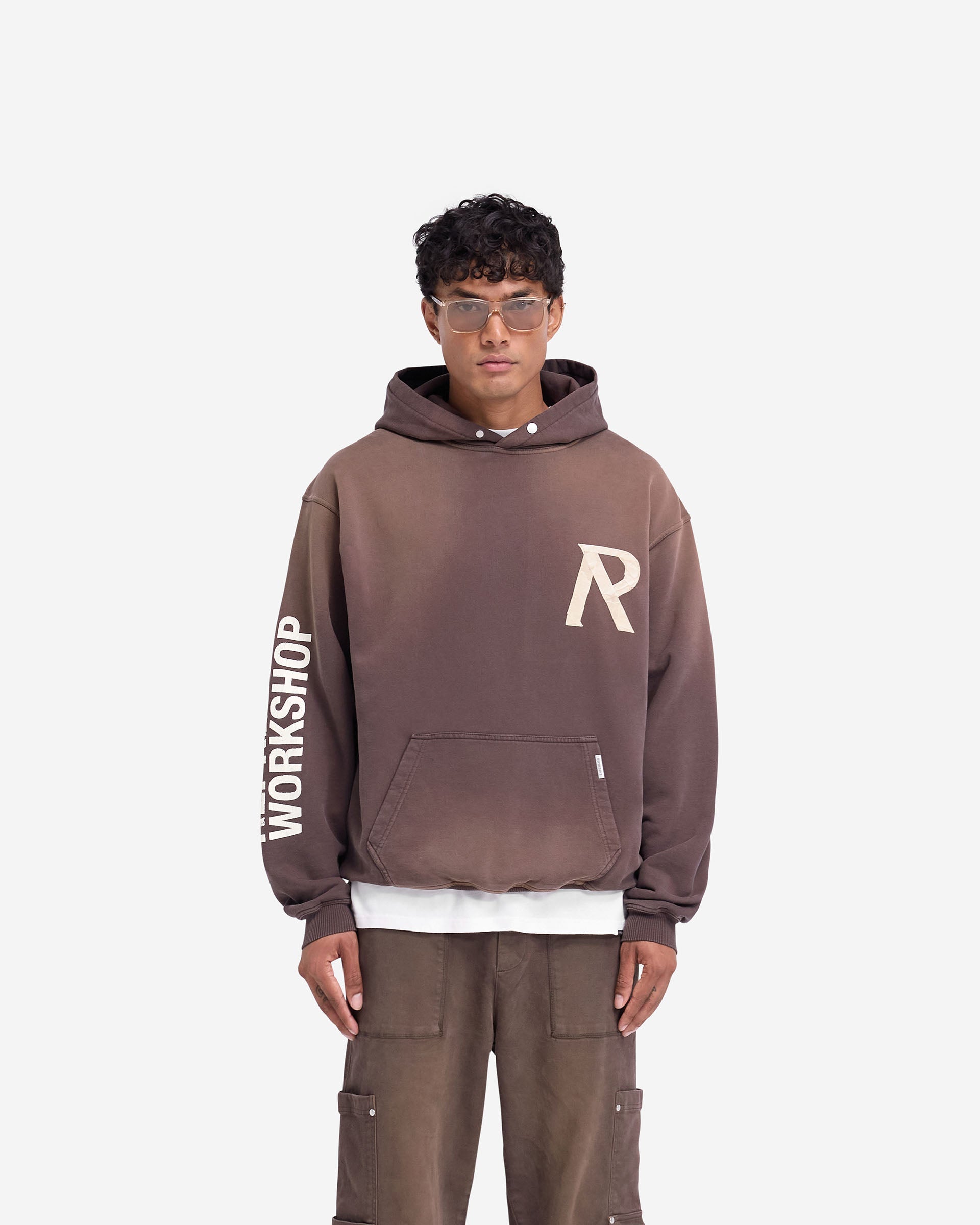 Man wearing a green hoodie on a plain white background | Masking Tape Initial Hoodie in Cedar | Slightly oversized hoodie with 3D tape effect | FW24 Hoodies | Represent Clo