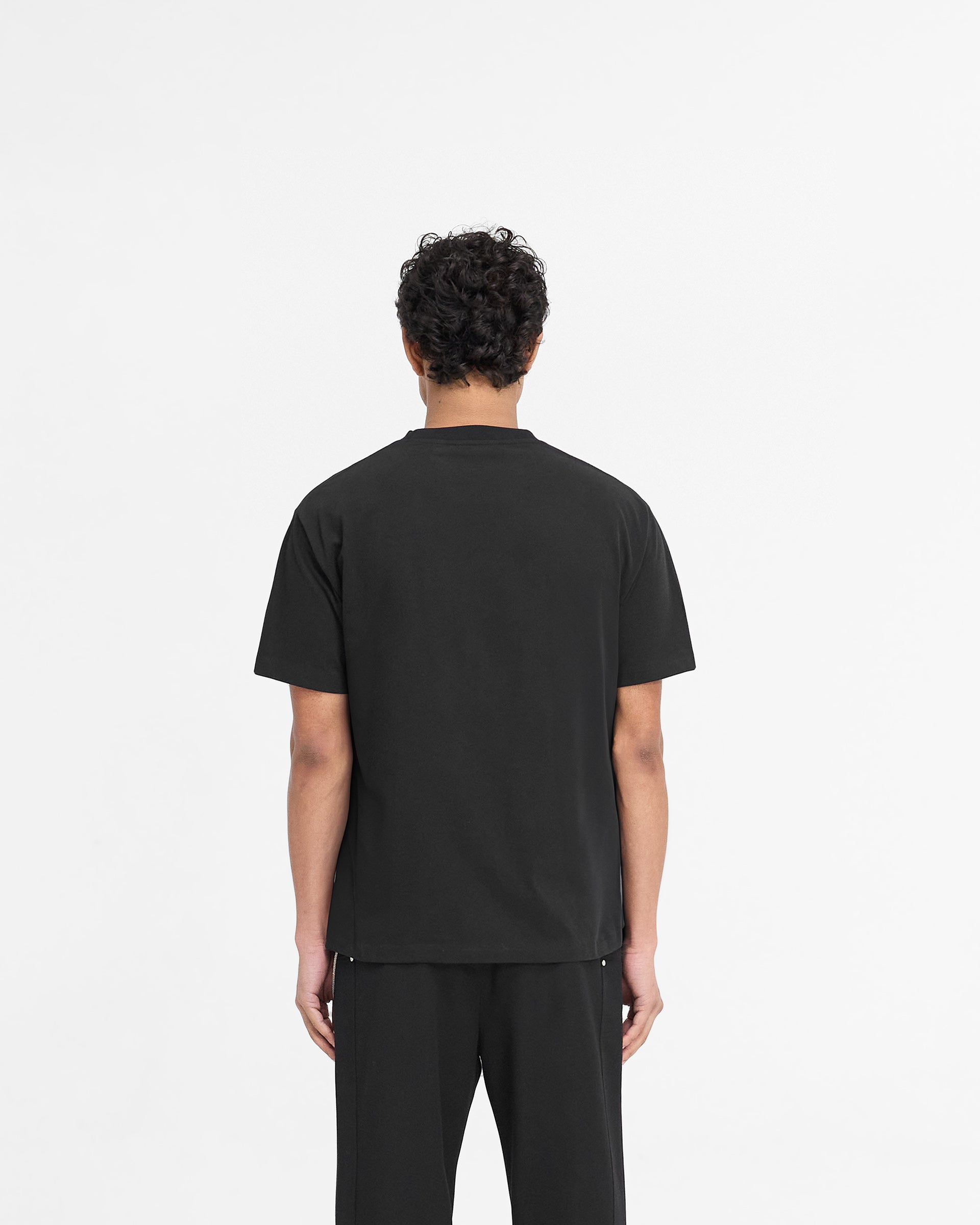 Man wearing a black t-shirt on a plain white background | Metal Initial R T-Shirt in Jet Black | Jersey cotton t-shirt with metal logo | PRE SS25 T-Shirts | Represent Clo